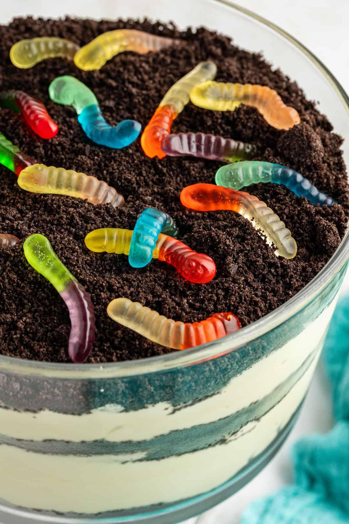 Primo piano di una grande ciotola da trifle di torta di terra guarnita con Oreo sbriciolati e vermi gommosi