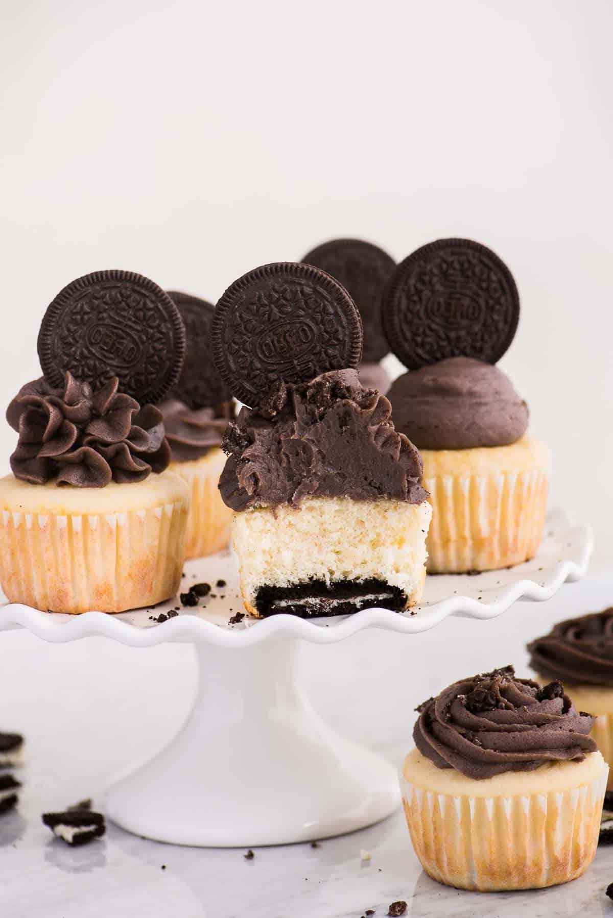 Cupcakes alla vaniglia con fondo Oreo su alzata bianca su sfondo bianco