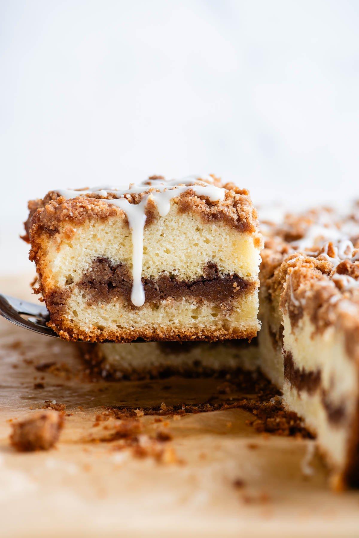 Una fetta di torta al caffè con glassa che cola sul lato, sollevata da una spatola dal resto della torta