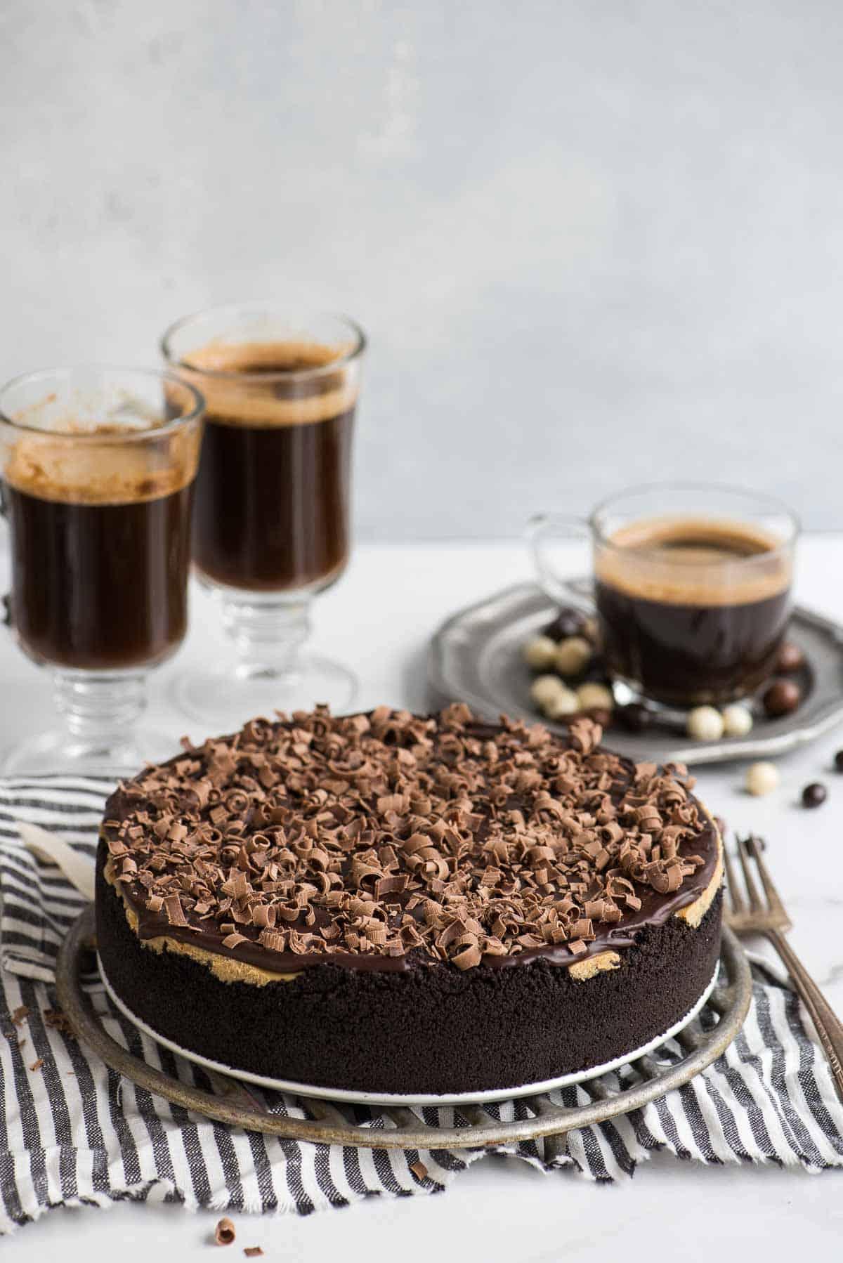 cheesecake all'espresso su alzata in metallo con tazzine da caffè sullo sfondo