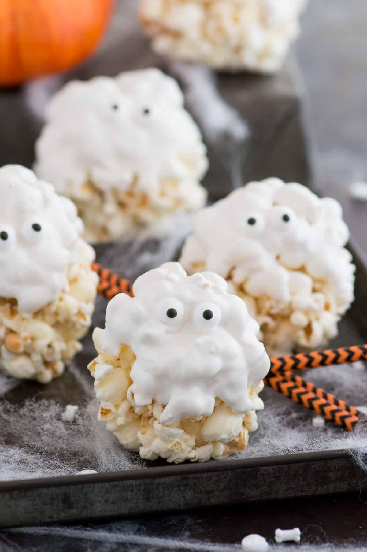 Palle di popcorn ricoperte di cioccolato bianco con occhietti di zucchero per assomigliare a fantasmi