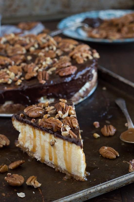 Questa è la migliore cheesecake tartaruga! È ricca e così cremosa. Guarnita con ganache al cioccolato, noci pecan e salsa al caramello.