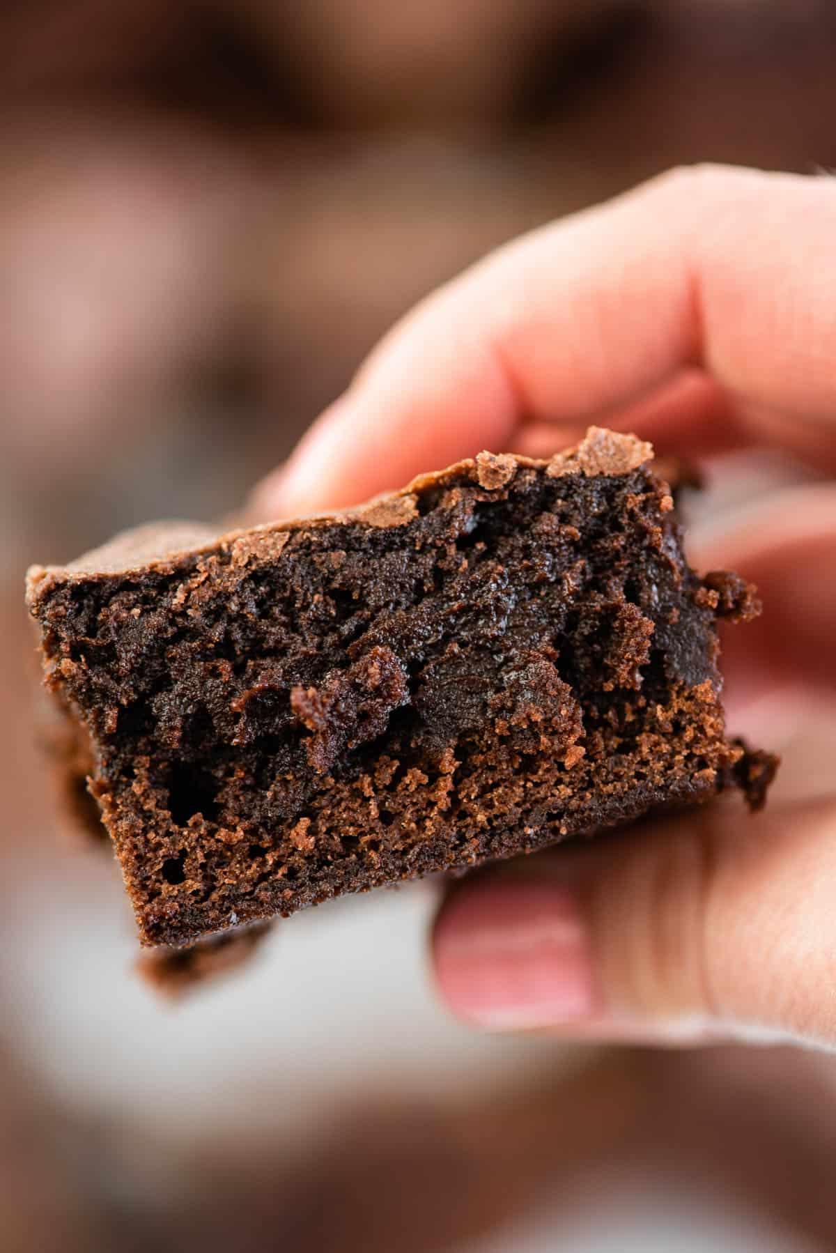 Trucchi per Brownie in Scatola 2 Mano che tiene una fetta di brownie fudgy