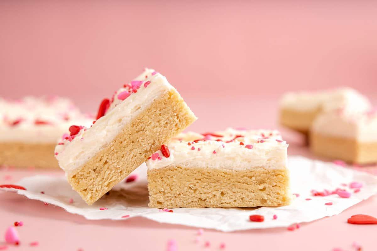 Quadrotti di Biscotti di Zucchero di San Valentino 2 due barrette di biscotto zuccherato con glassa bianca e confettini a tema San Valentino su sfondo rosa