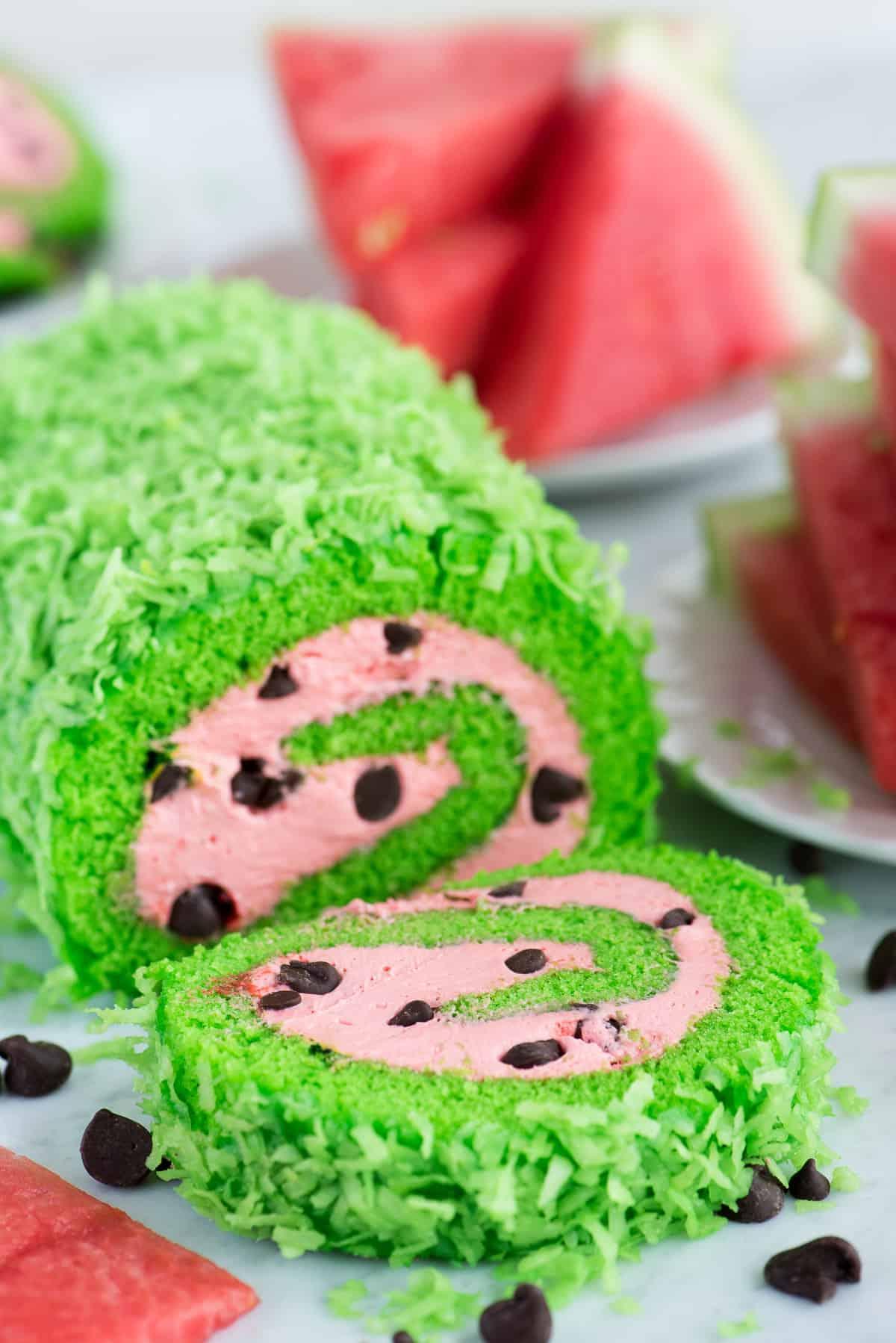 Rotolo all'Anguria 2 Una torta rotolo verde brillante con un ripieno rosa intenso e gocce di cioccolato che imitano i semi di anguria.