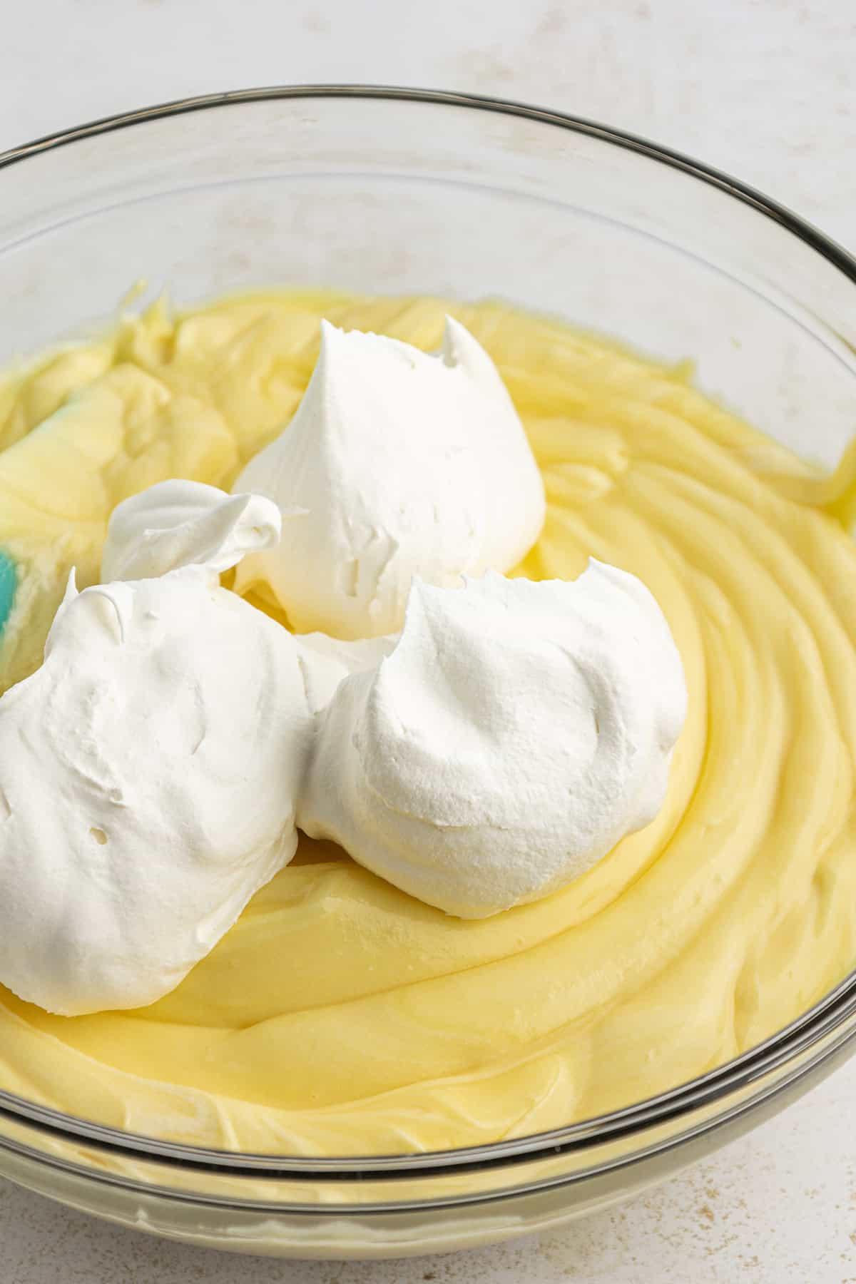 Miscela di budino istantaneo alla vaniglia in una ciotola di vetro trasparente guarnita con panna montata non ancora mescolata