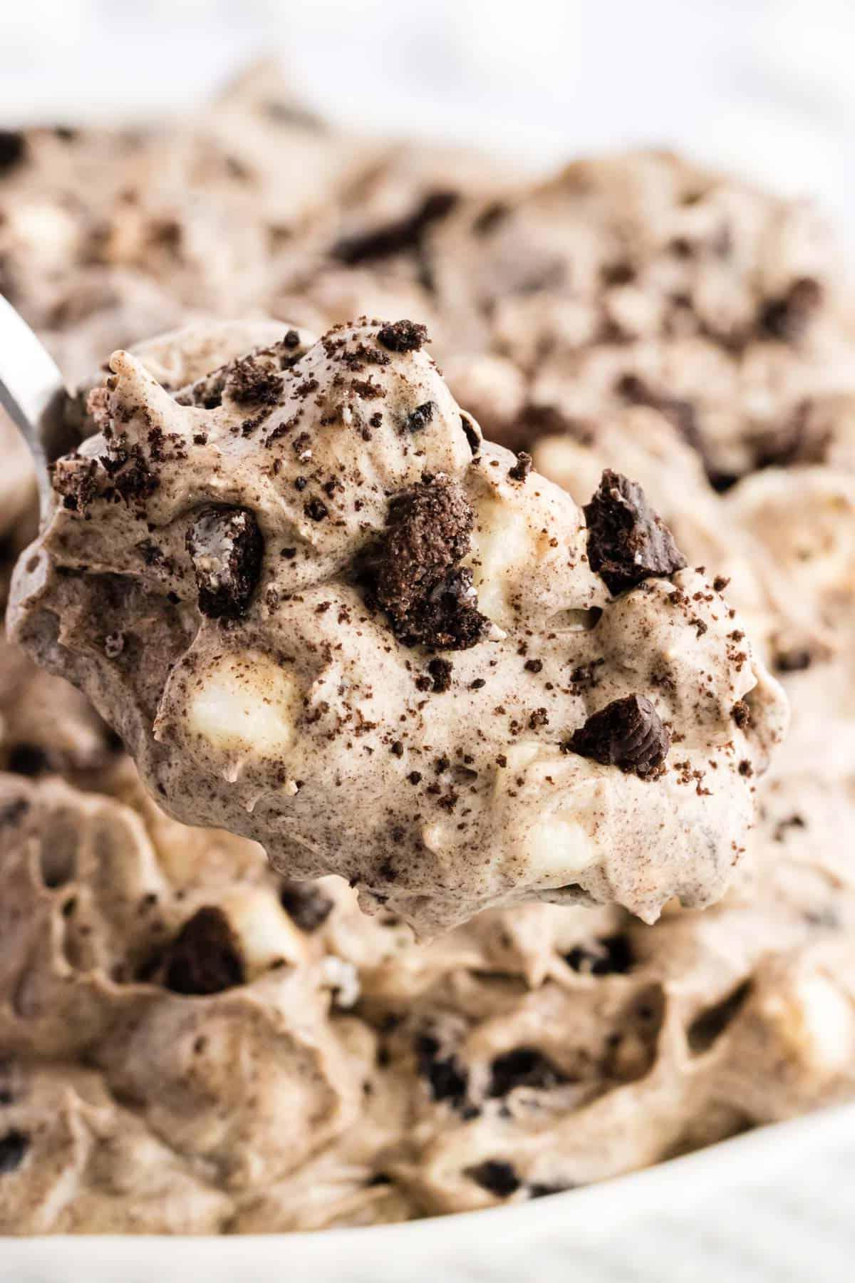 Primo piano di un cucchiaio pieno di fluff di Oreo sollevato da una ciotola piena di fluff di Oreo