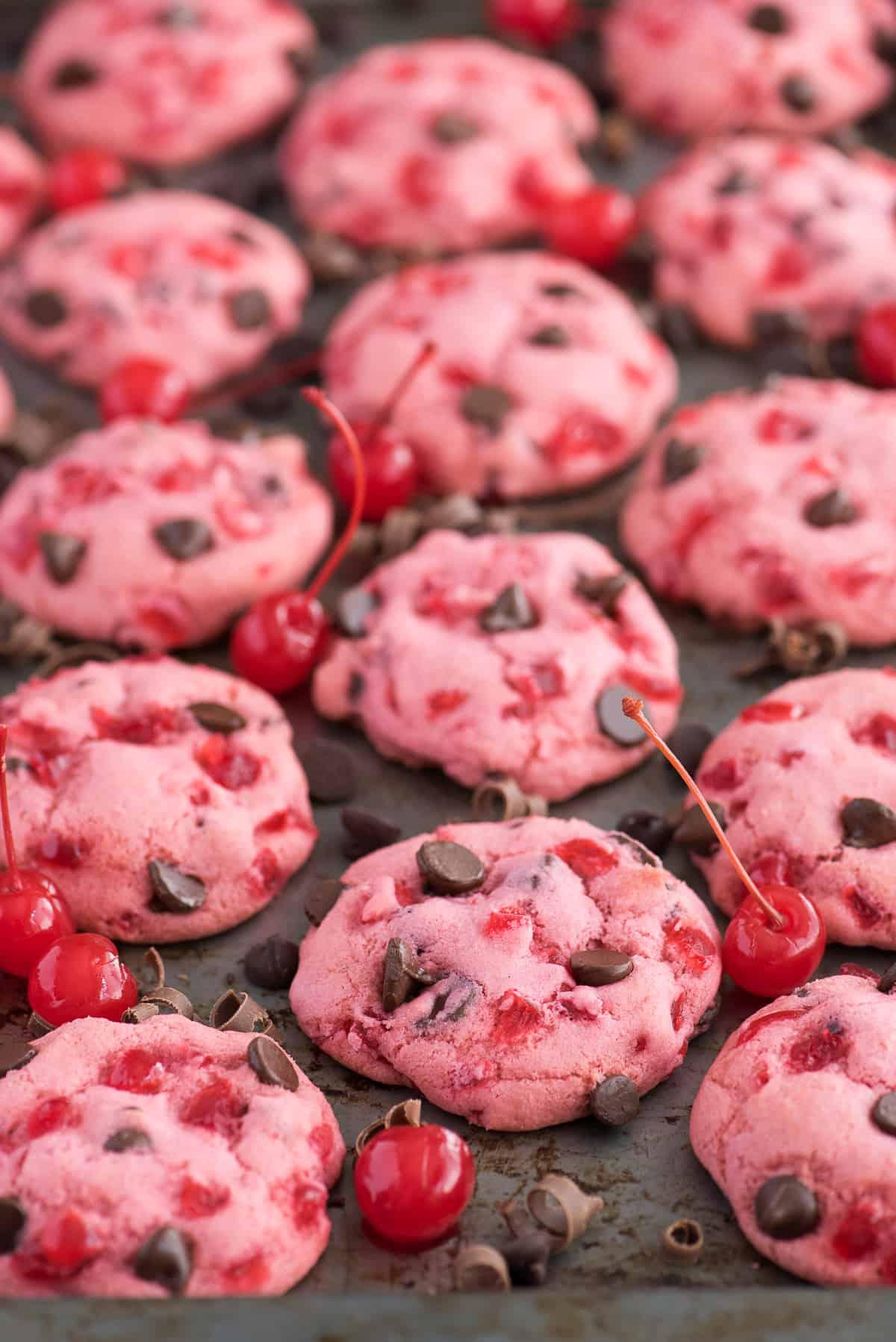 biscotti rosa alle ciliegie maraschino e gocce di cioccolato su teglia con ciliegie e gocce di cioccolato