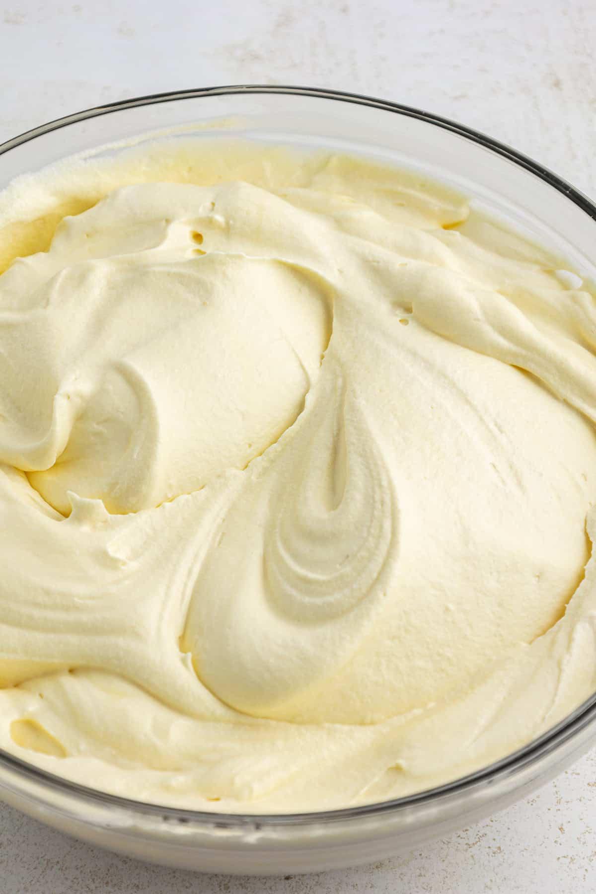 Latte e budino istantaneo alla vaniglia mescolati in una grande ciotola di vetro trasparente