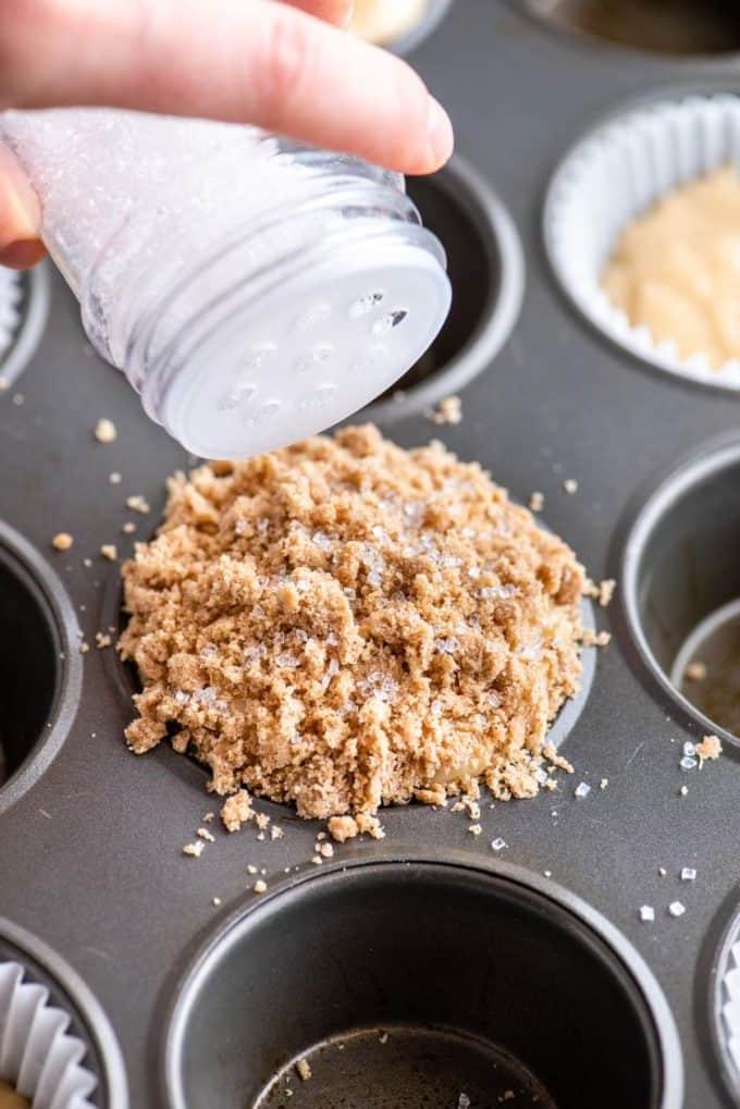 mano che aggiunge zucchero bianco granulato sulla parte superiore del muffin