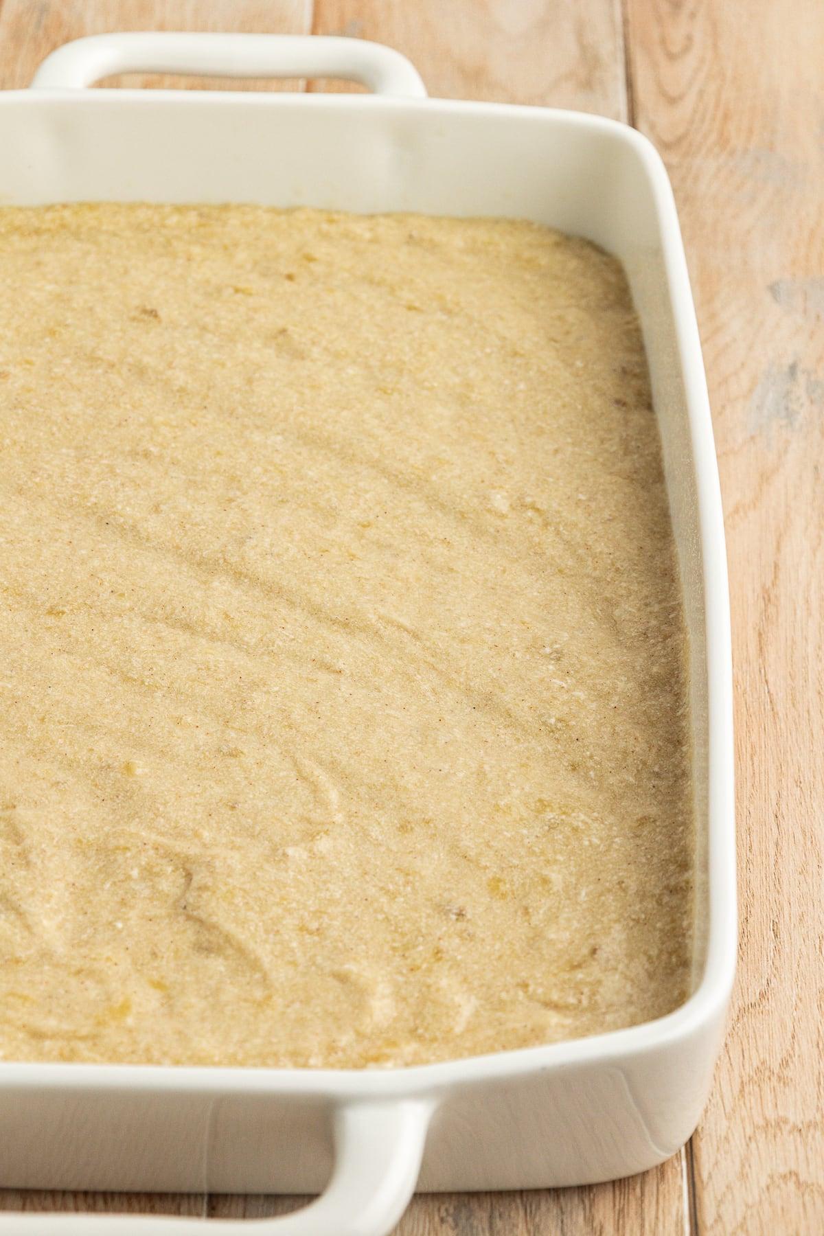 Impasto di torta di banane in una teglia bianca da 9x13 su una superficie di legno