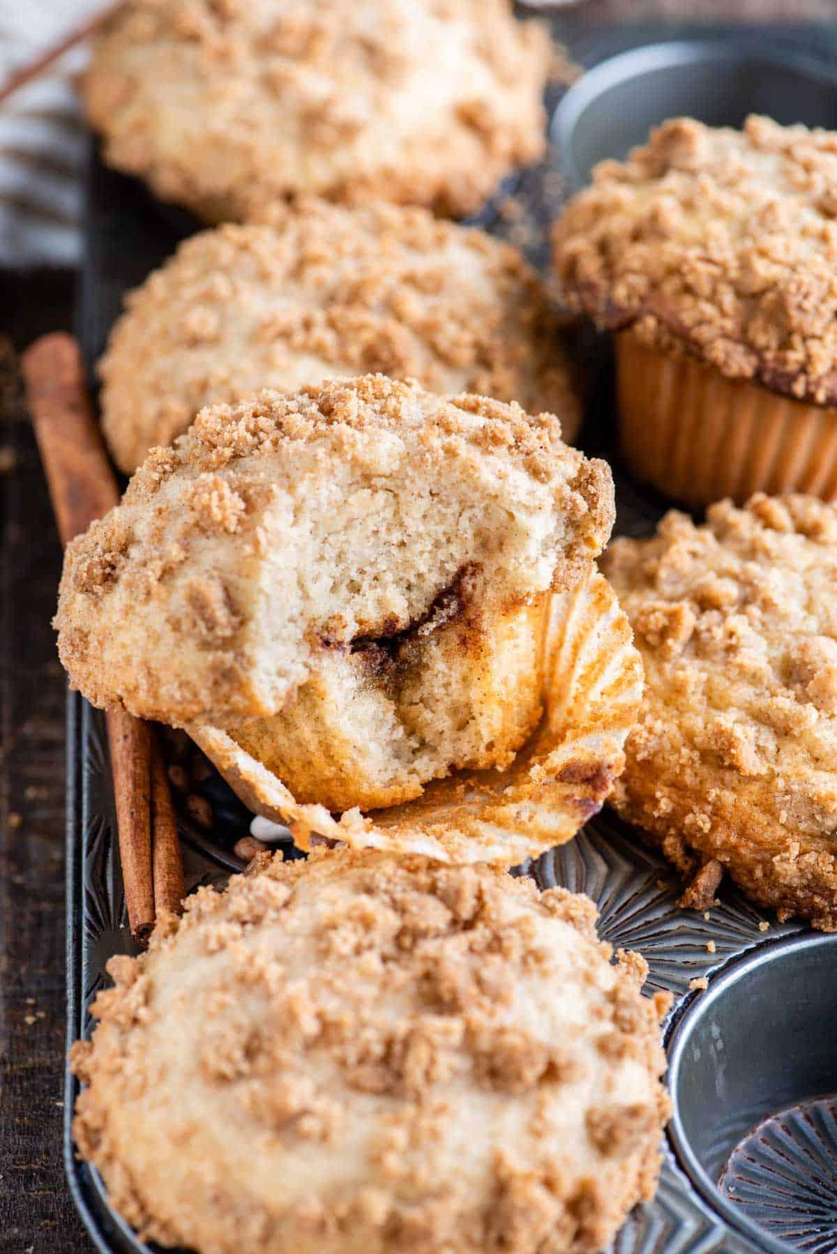 muffin al caffè con un morso che mostra lo strato di cannella all'interno nella teglia da muffin metallica