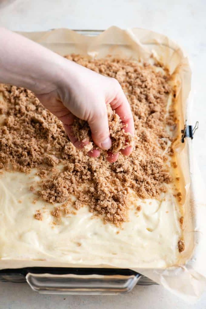 Topping di crumble sparso sull'impasto della torta al caffè in una teglia foderata con carta forno