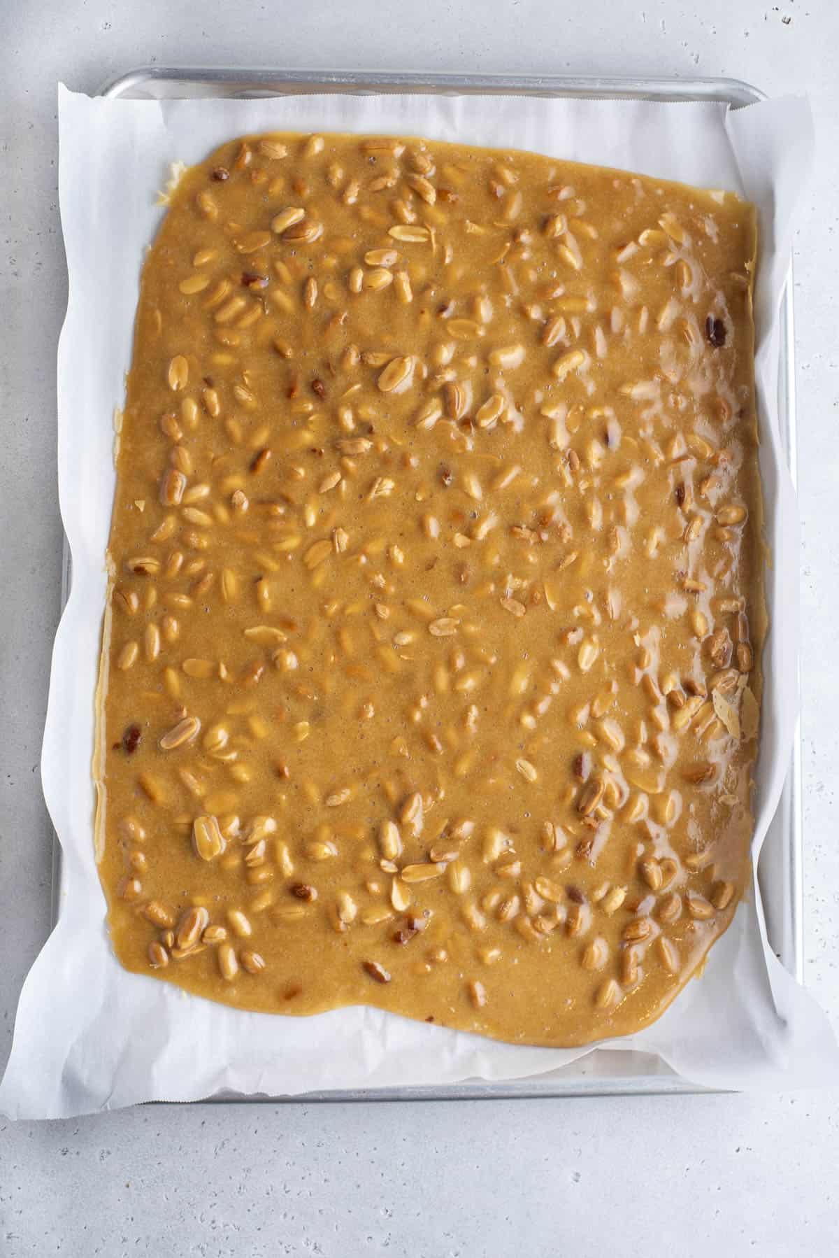 Miscela di croccante di arachidi versata su una teglia rivestita di carta da forno