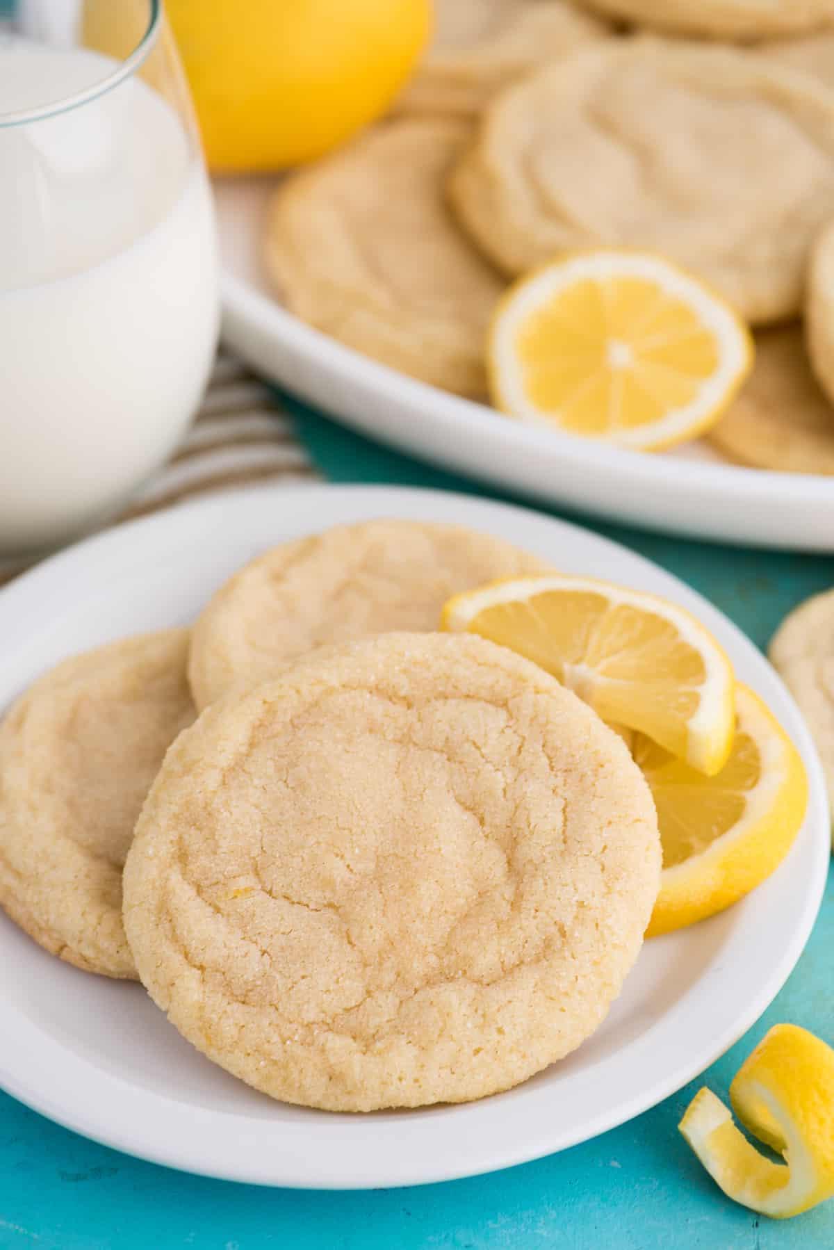Biscotti al limone su piatto bianco con bicchiere di latte su sfondo blu
