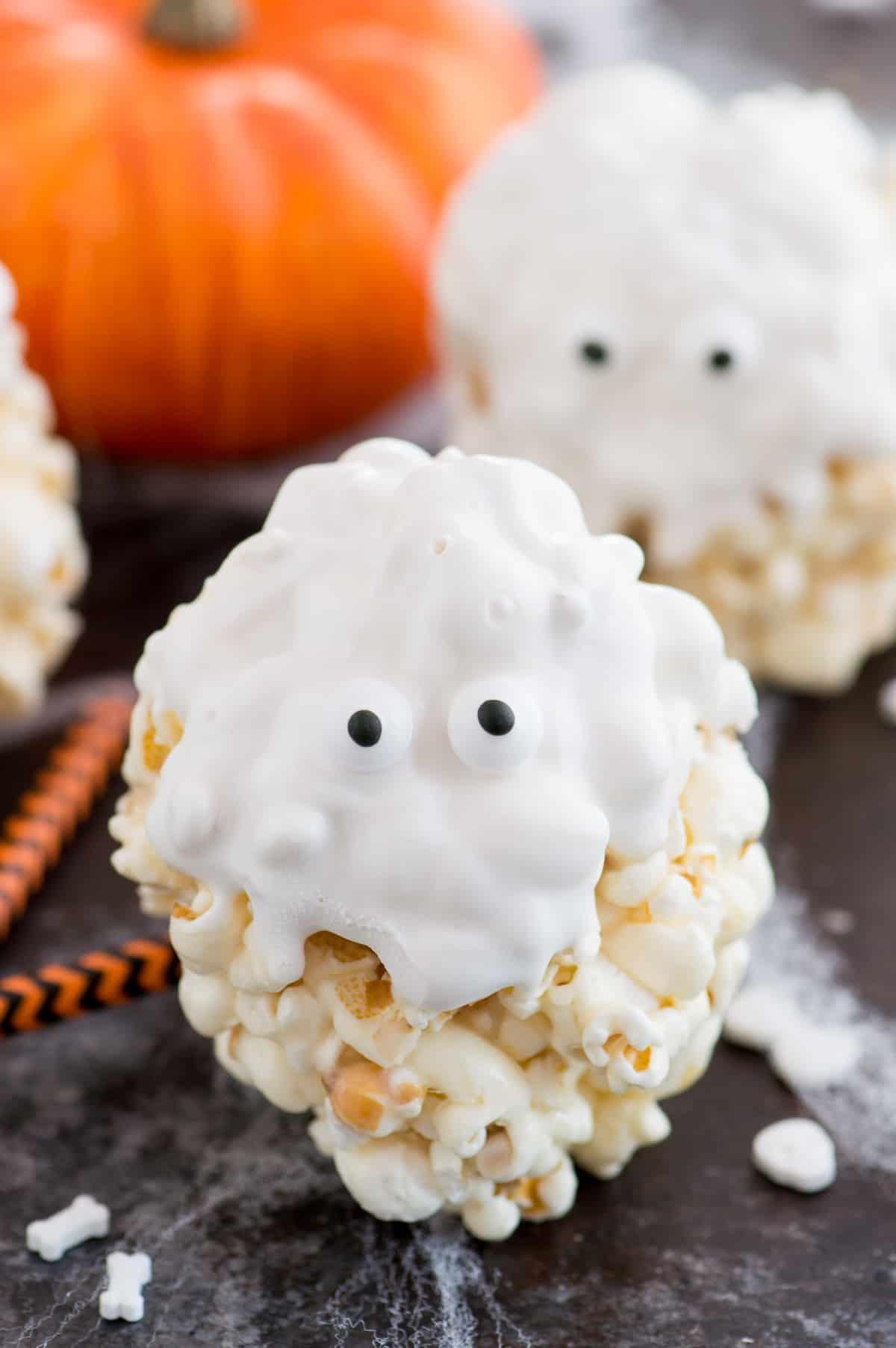 Palle di popcorn ricoperte di cioccolato bianco con occhietti di zucchero per assomigliare a fantasmi
