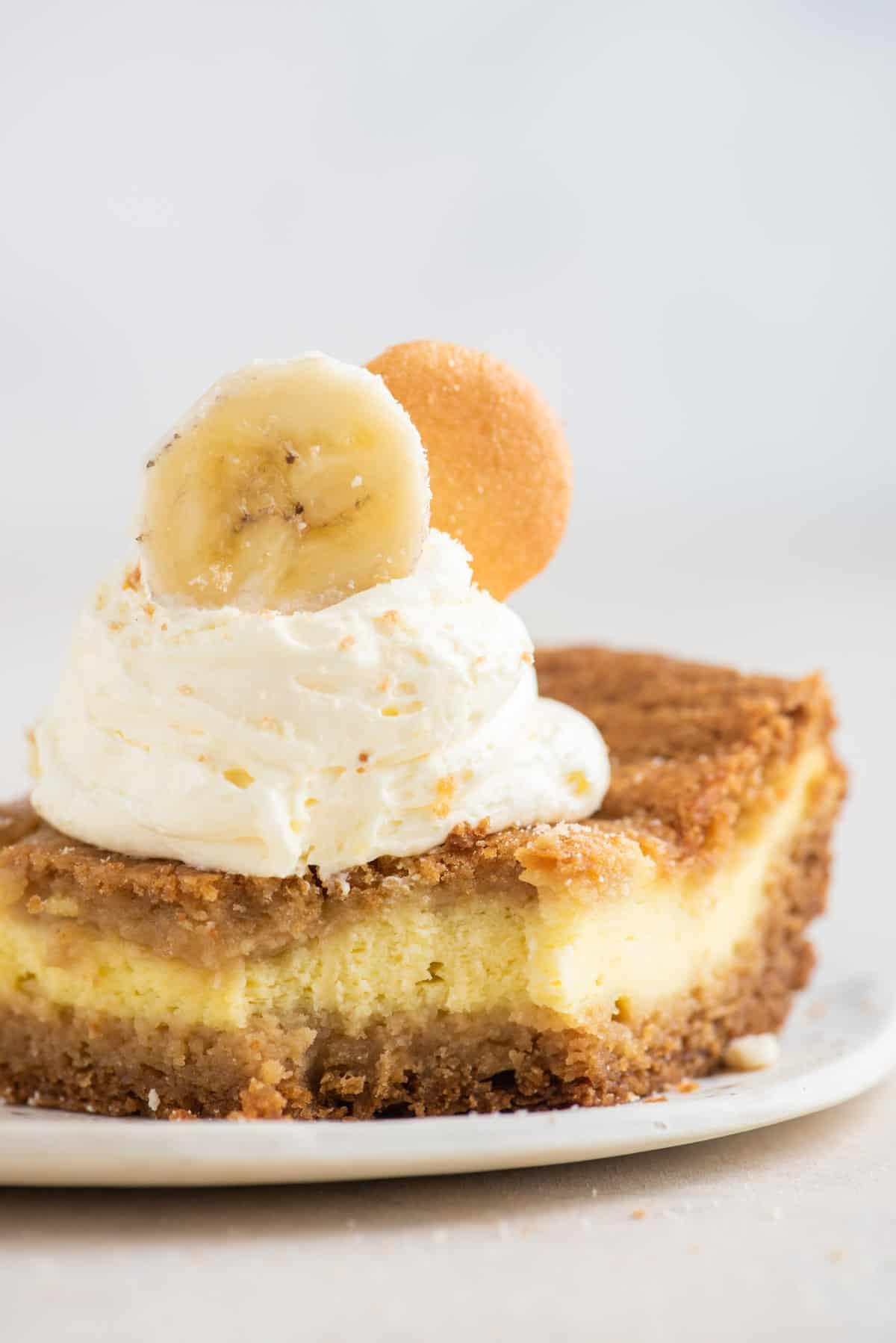 Un brownie al budino di banana su un piatto guarnito con panna montata, una fetta di banana e un wafer alla vaniglia