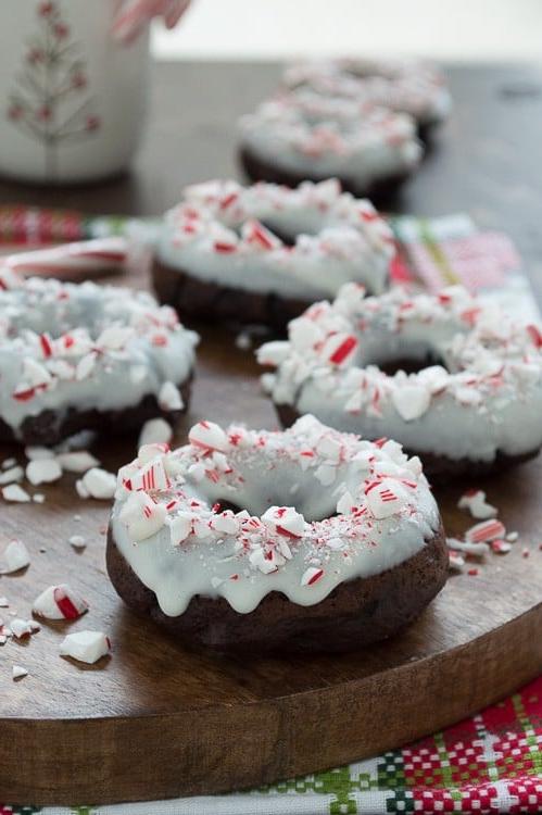 Ciambelle al Cioccolato e Bastoncino di Zucchero 3 Ciambelle al cioccolato cotte al forno, aromatizzate alla menta piperita, guarnite con cioccolato bianco e bastoncini di zucchero tritati.