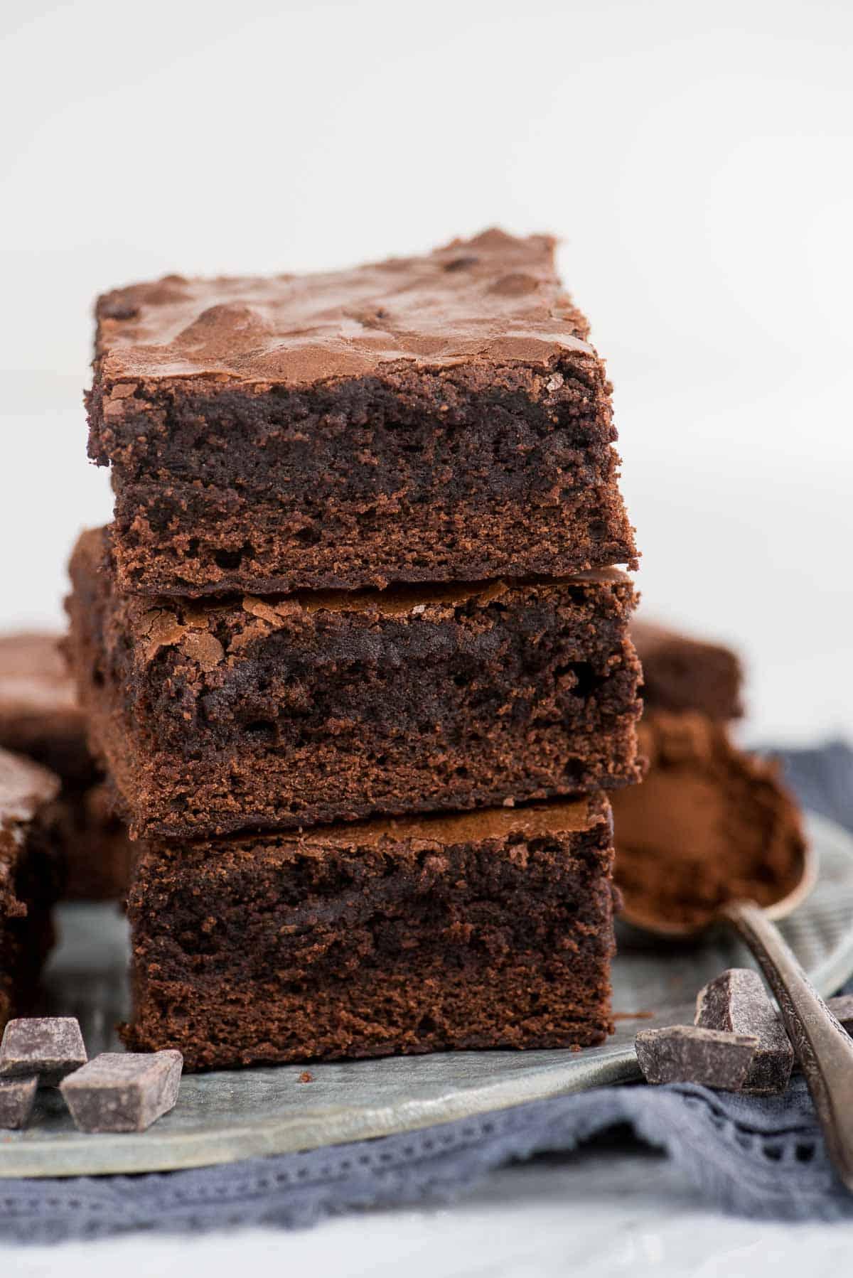 Trucchi per Brownie in Scatola 3 Tre brownies impilati su un piatto grigio con un tovagliolo blu