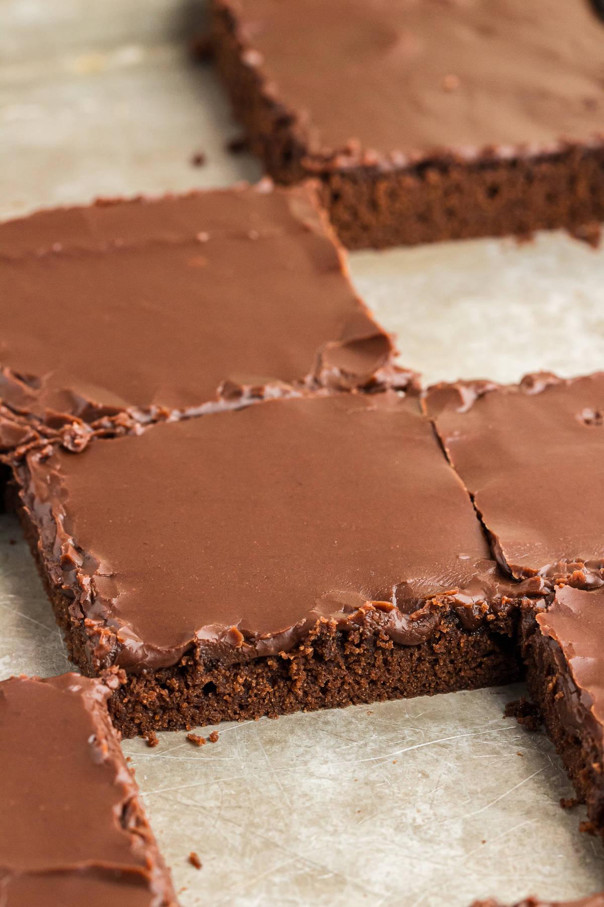 Primo piano di fette quadrate di torta su una teglia con alcuni quadrati vuoti dove mancano fette