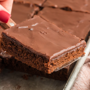 Una fetta di torta Texana al cioccolato sollevata da una teglia piena di fette di torta