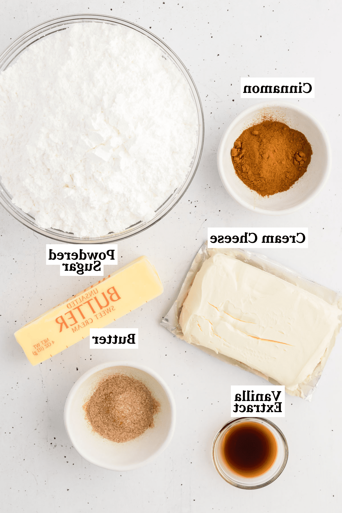 Ingredientes para glaseado de queso crema con canela, incluyendo canela, azúcar en polvo, queso crema, mantequilla, extracto de vainilla y azúcar de canela