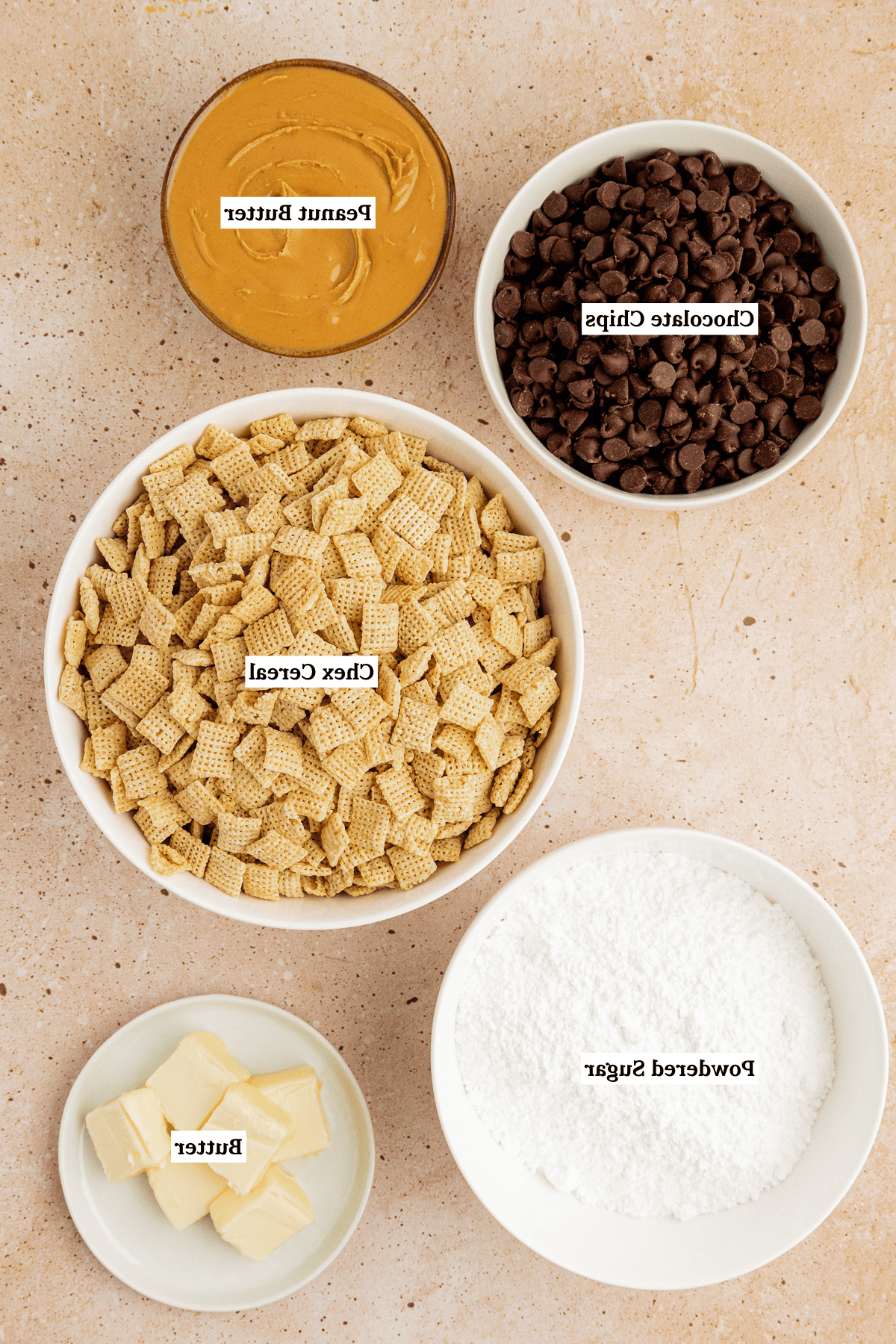 Vista dall'alto degli ingredienti del puppy chow, inclusi cereali chex, zucchero a velo, gocce di cioccolato, burro d'arachidi e burro