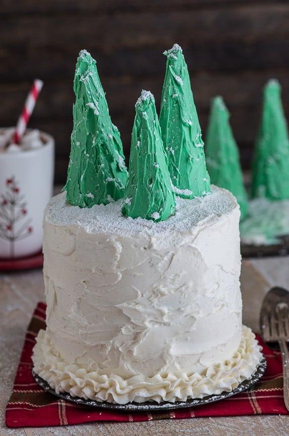 Torta di pan di zenzero festiva a più strati con ricca crema al burro alla vaniglia, impreziosita da adorabili alberi di Natale in glassa