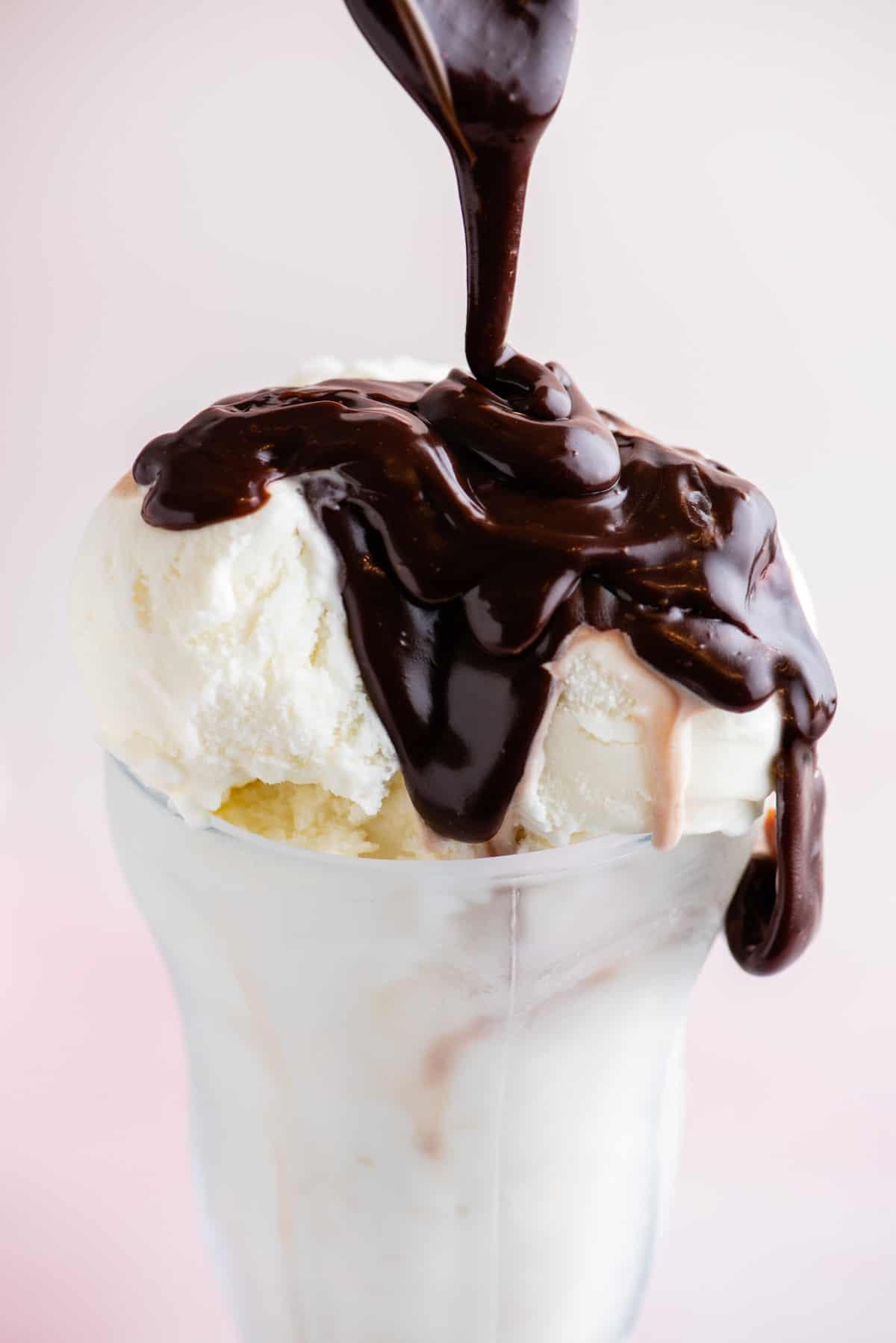 Salsa hot fudge versata su gelato in una coppa di vetro