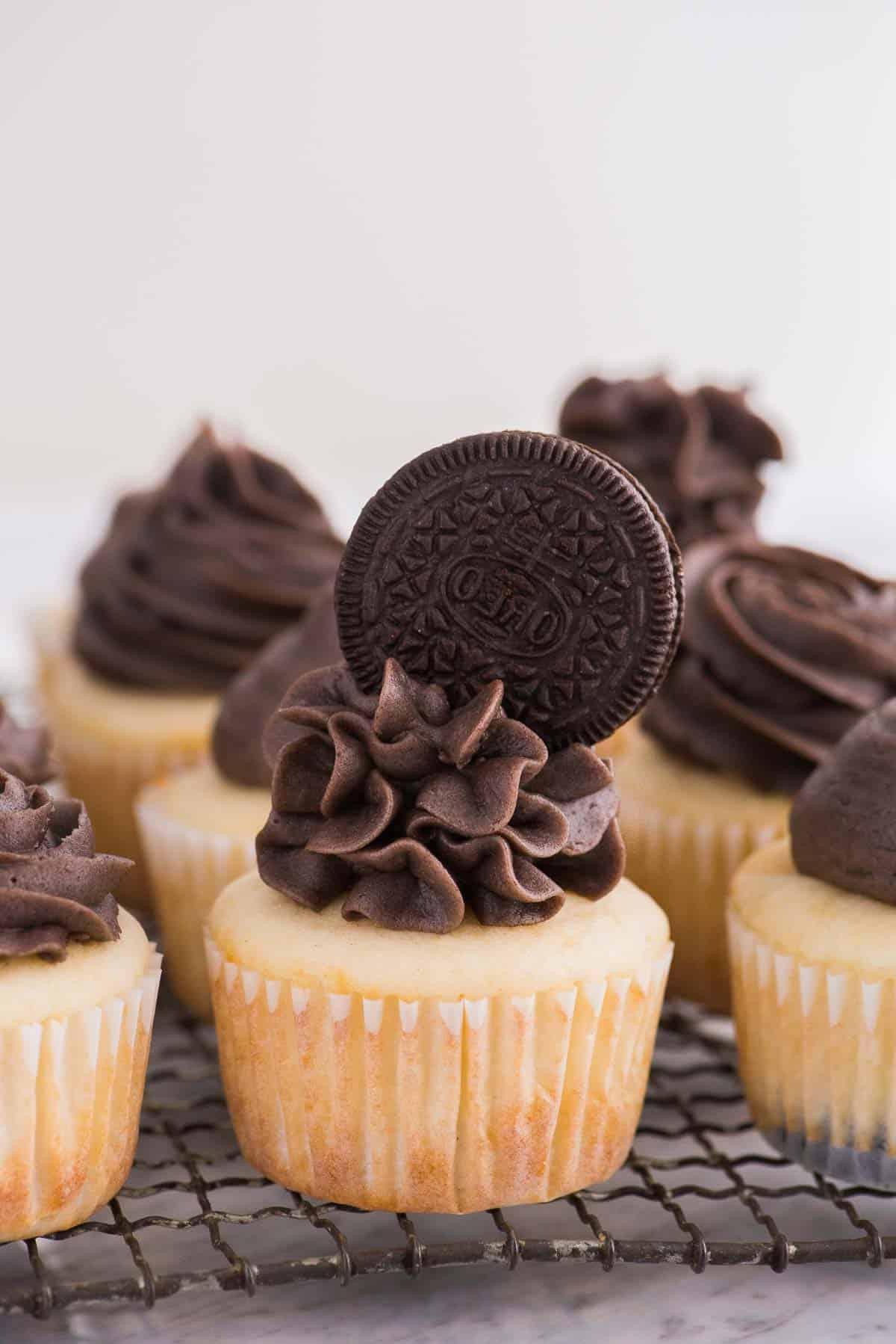 Cupcakes alla vaniglia con glassa Oreo e biscotto Oreo intero in cima su una griglia di raffreddamento