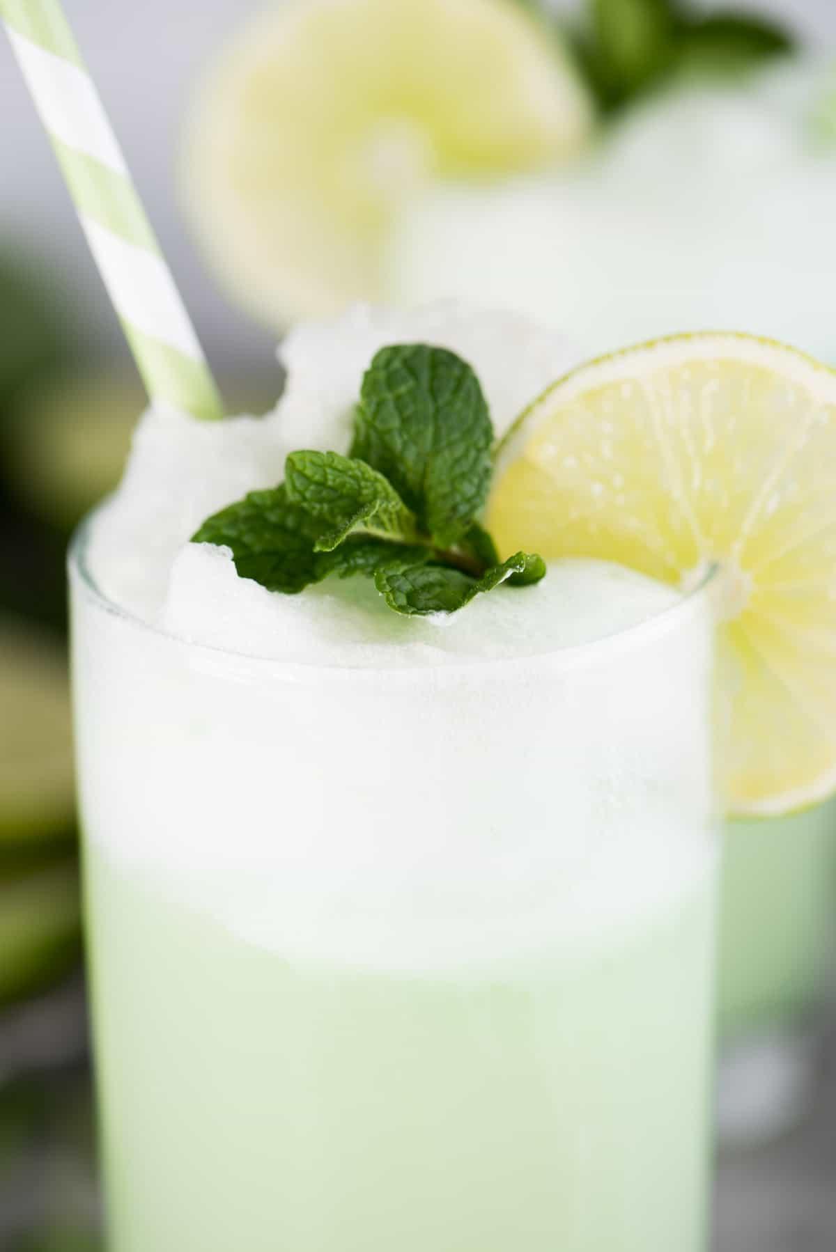 Float rinfrescante al sorbetto al lime in bicchiere con fetta di lime, foglie di menta e cannuccia verde.