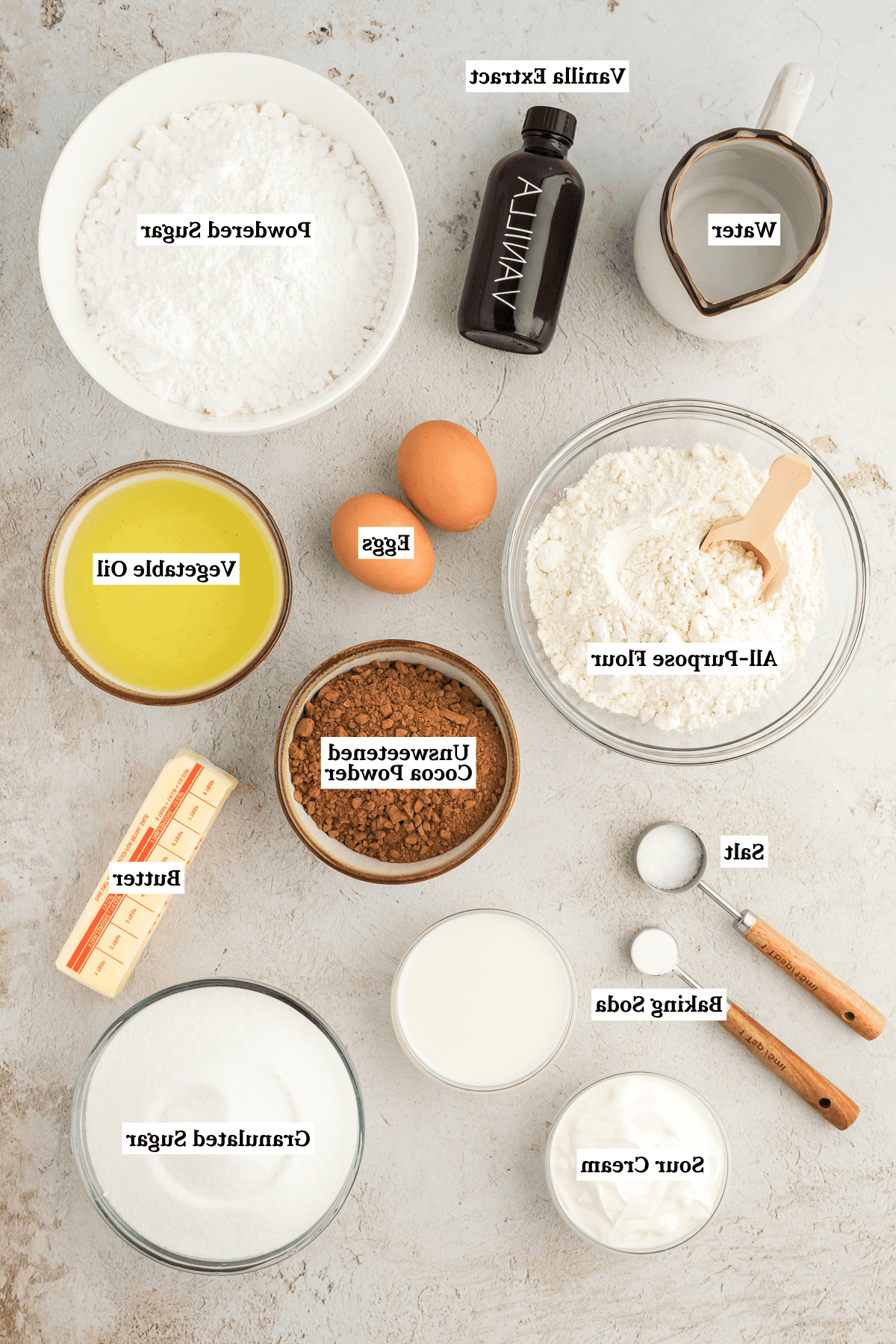 Ingredienti per la torta Texana, inclusi acqua, estratto di vaniglia, zucchero a velo, farina 00, olio vegetale, cacao amaro in polvere, burro, sale, bicarbonato di sodio, panna acida, zucchero semolato e latte
