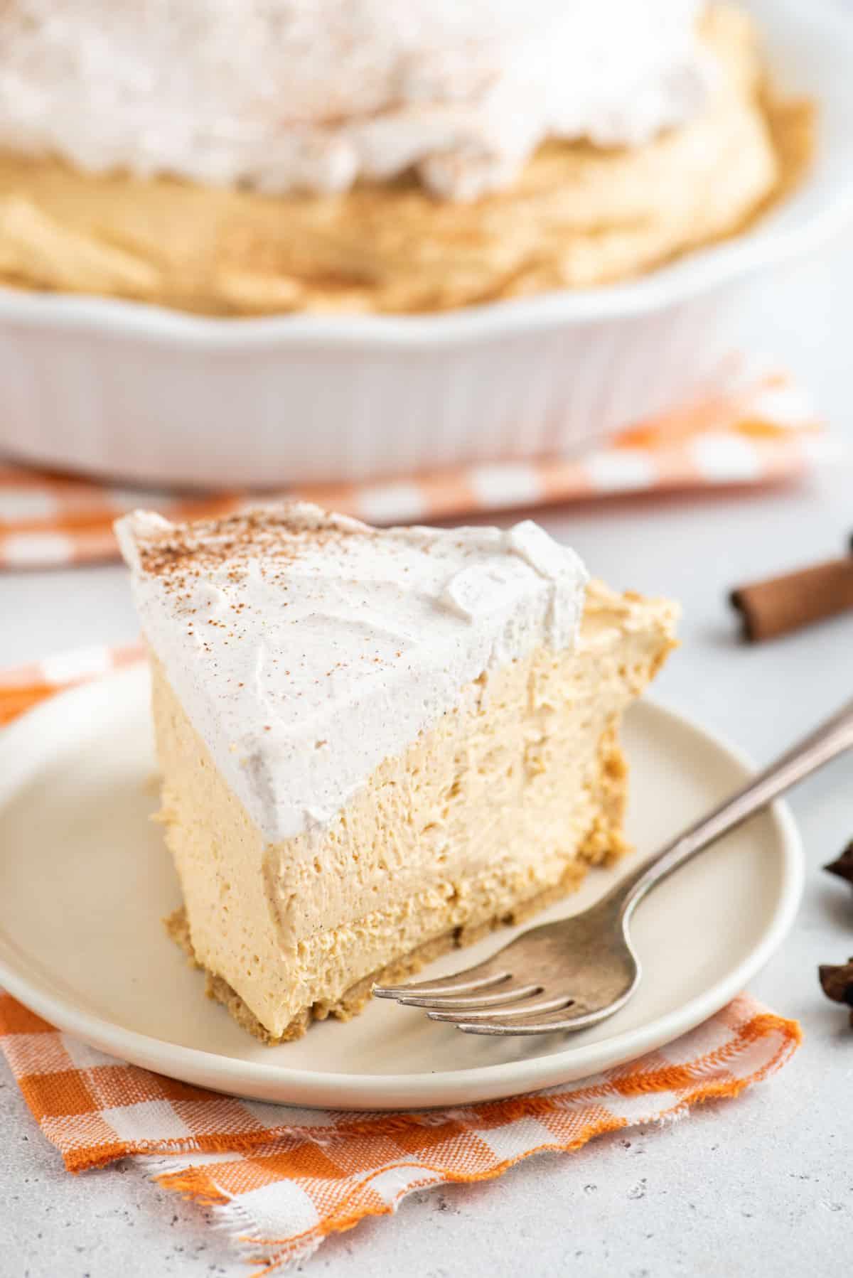 Una forchetta è appoggiata accanto a una fetta di torta di zucca senza cottura.