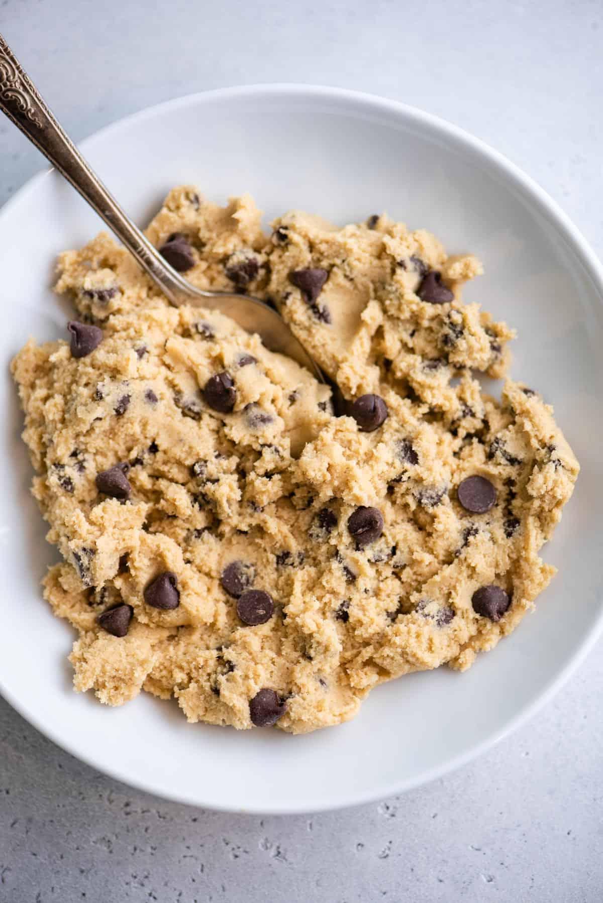 Visuale dall'alto dell'impasto dei biscotti con gocce di cioccolato in una ciotola con un cucchiaio