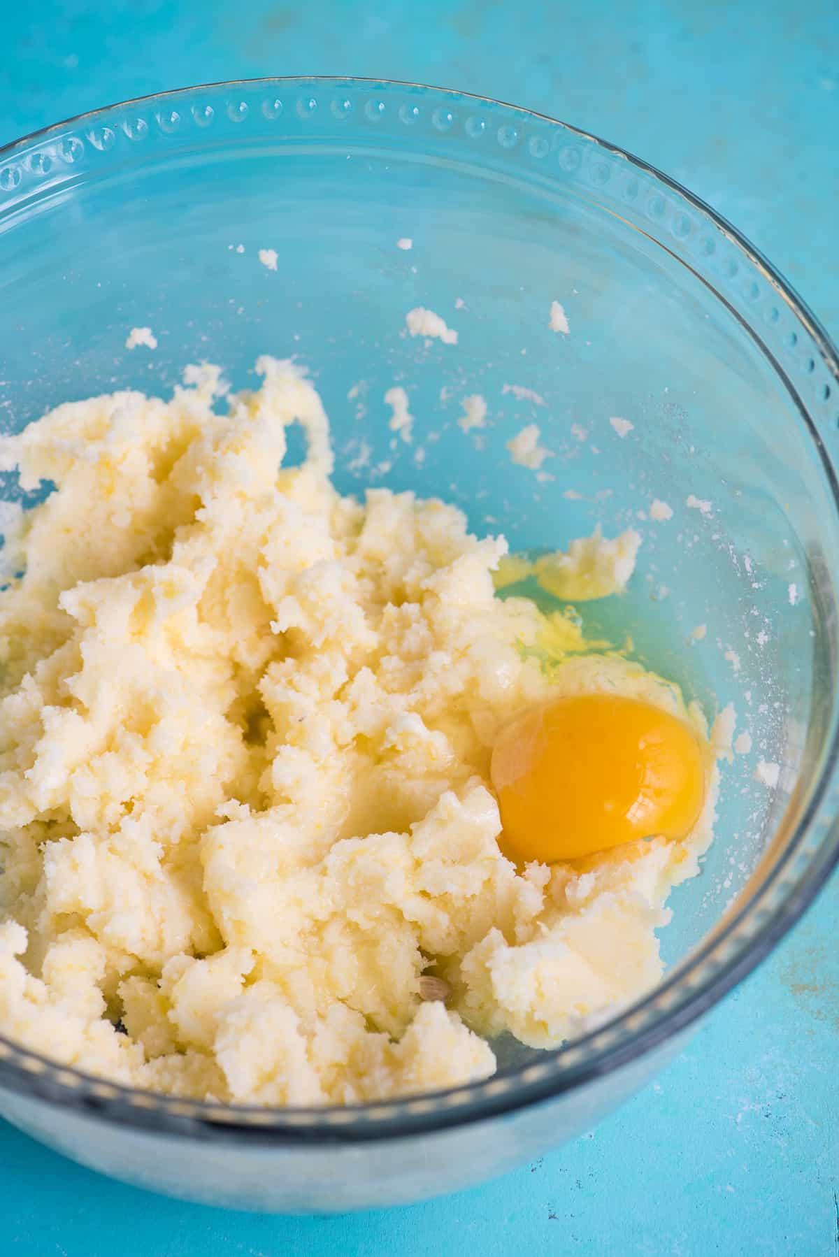 Impasto per biscotti con uovo in una ciotola di vetro su sfondo blu
