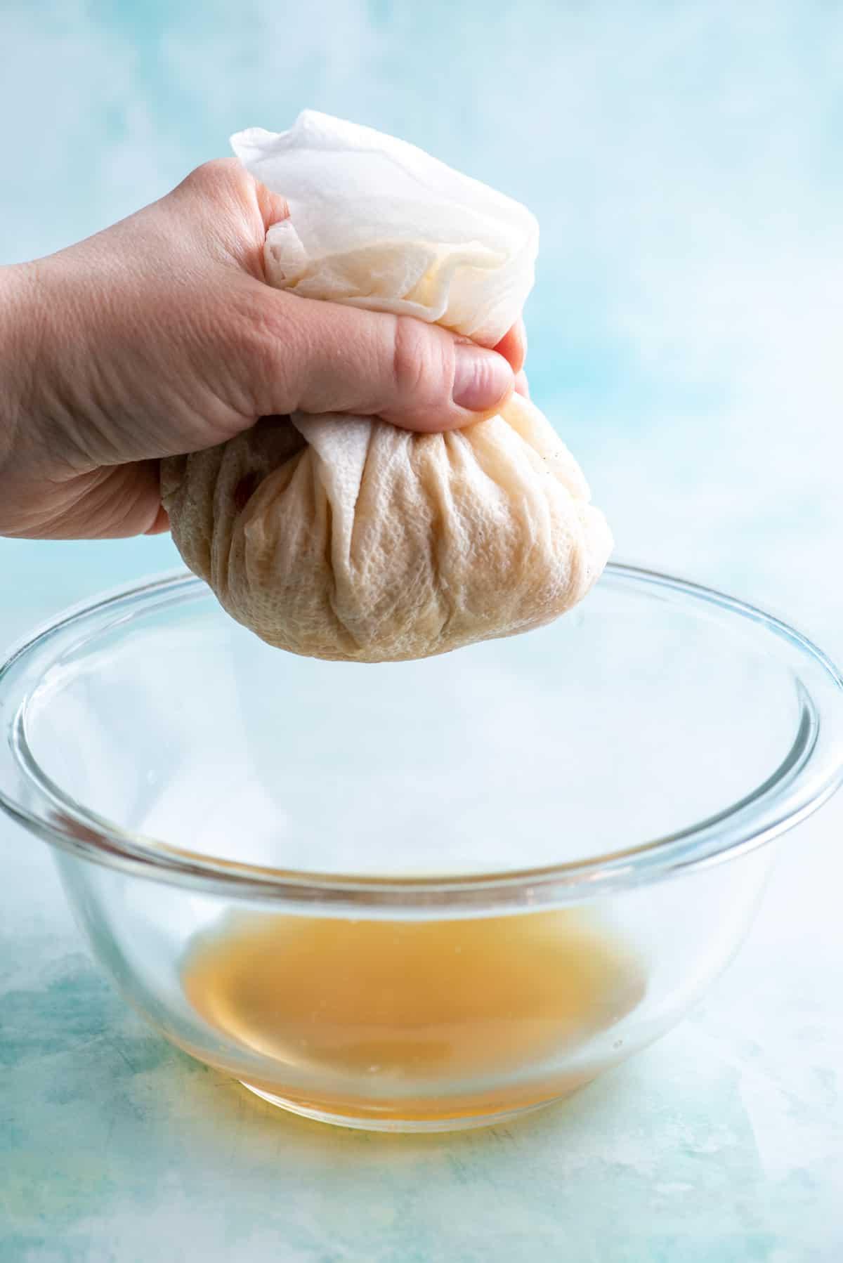Mele avvolte in carta assorbente vengono spremute sopra una ciotola di vetro per rimuovere il liquido in eccesso.