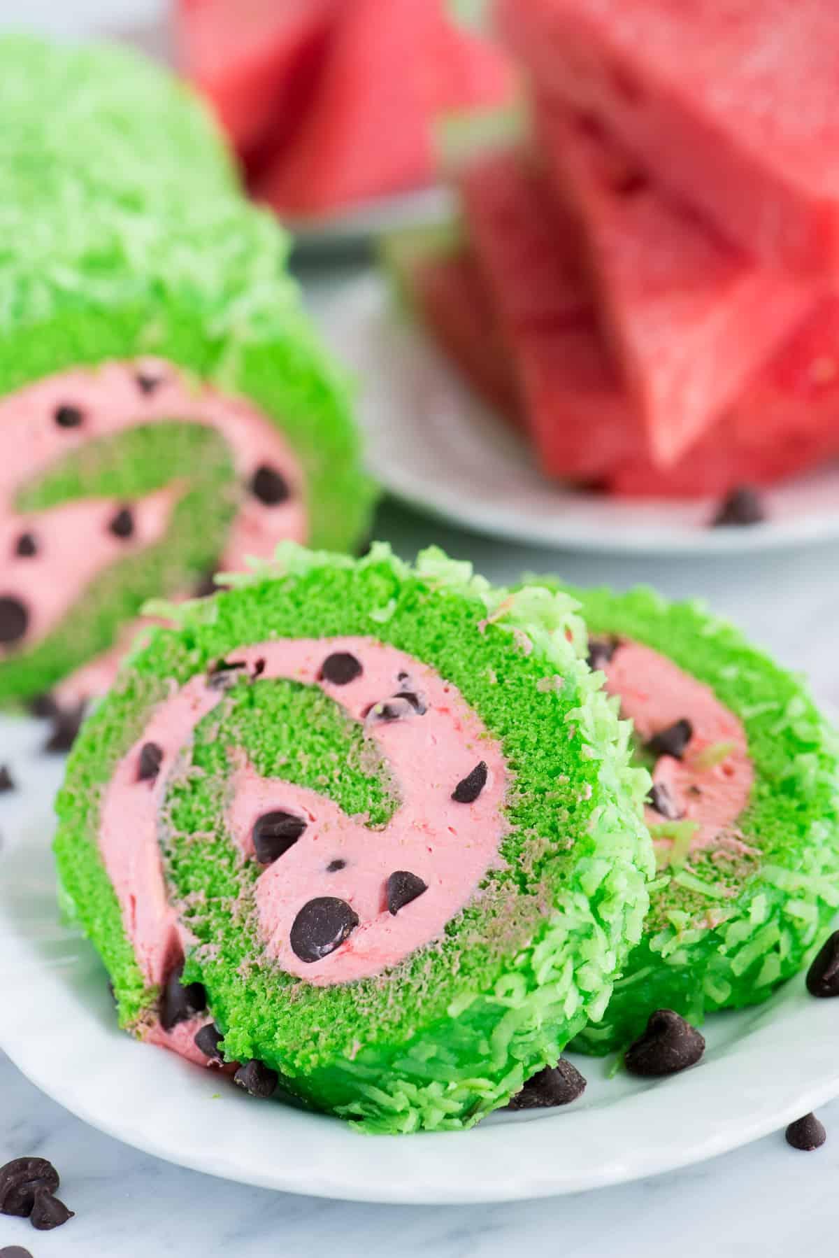 Rotolo all'Anguria 5 Una torta rotolo con ripieno rosa e gocce di cioccolato, distesa su un canovaccio spolverato di zucchero a velo, pronta per essere arrotolata.