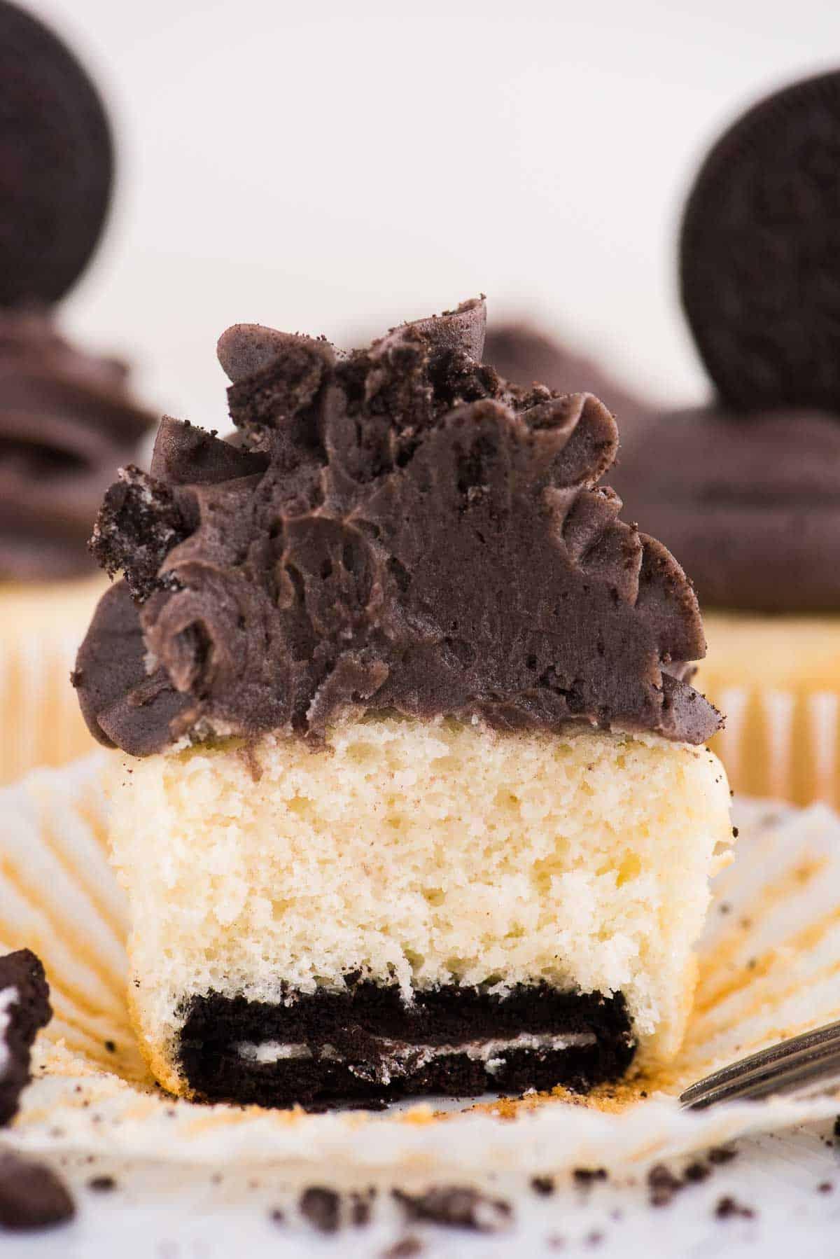 Cupcake alla vaniglia con fondo Oreo tagliato a metà su sfondo bianco