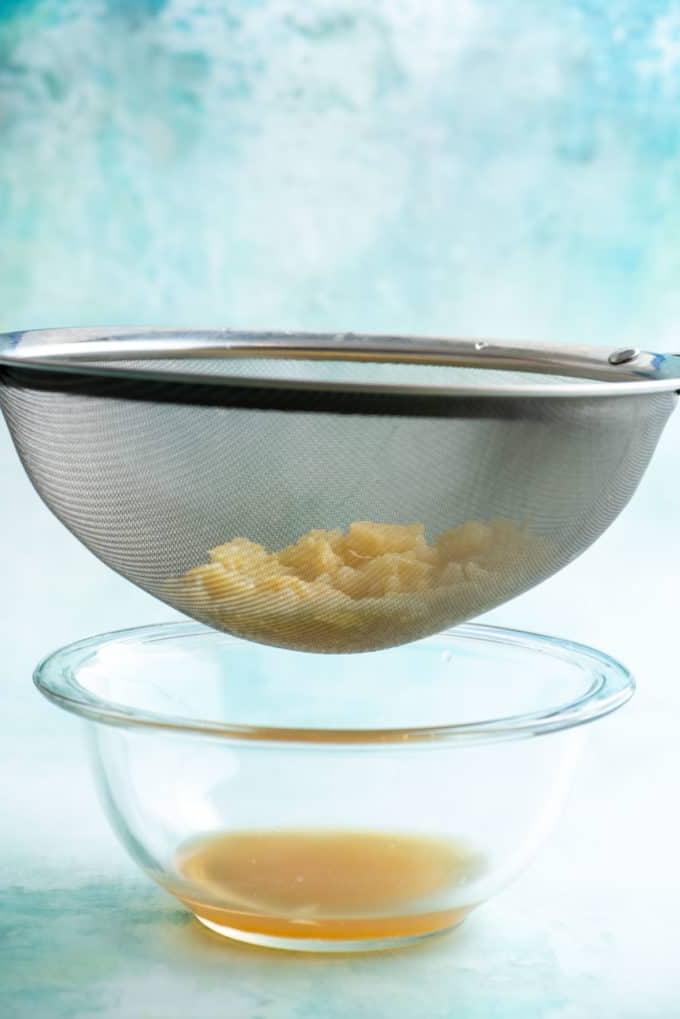 Ananas tritato viene scolato sopra una ciotola di vetro per rimuovere il liquido in eccesso.