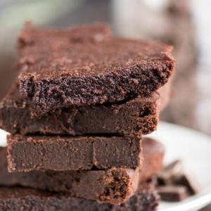 Cinque brownies fondenti salutari fatti in casa su un piatto da portata bianco.
