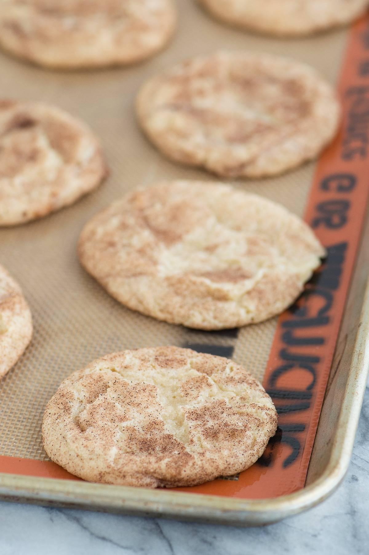 Snickerdoodle alle mele caramellate allineati su un tappetino di silicone su una teglia metallica