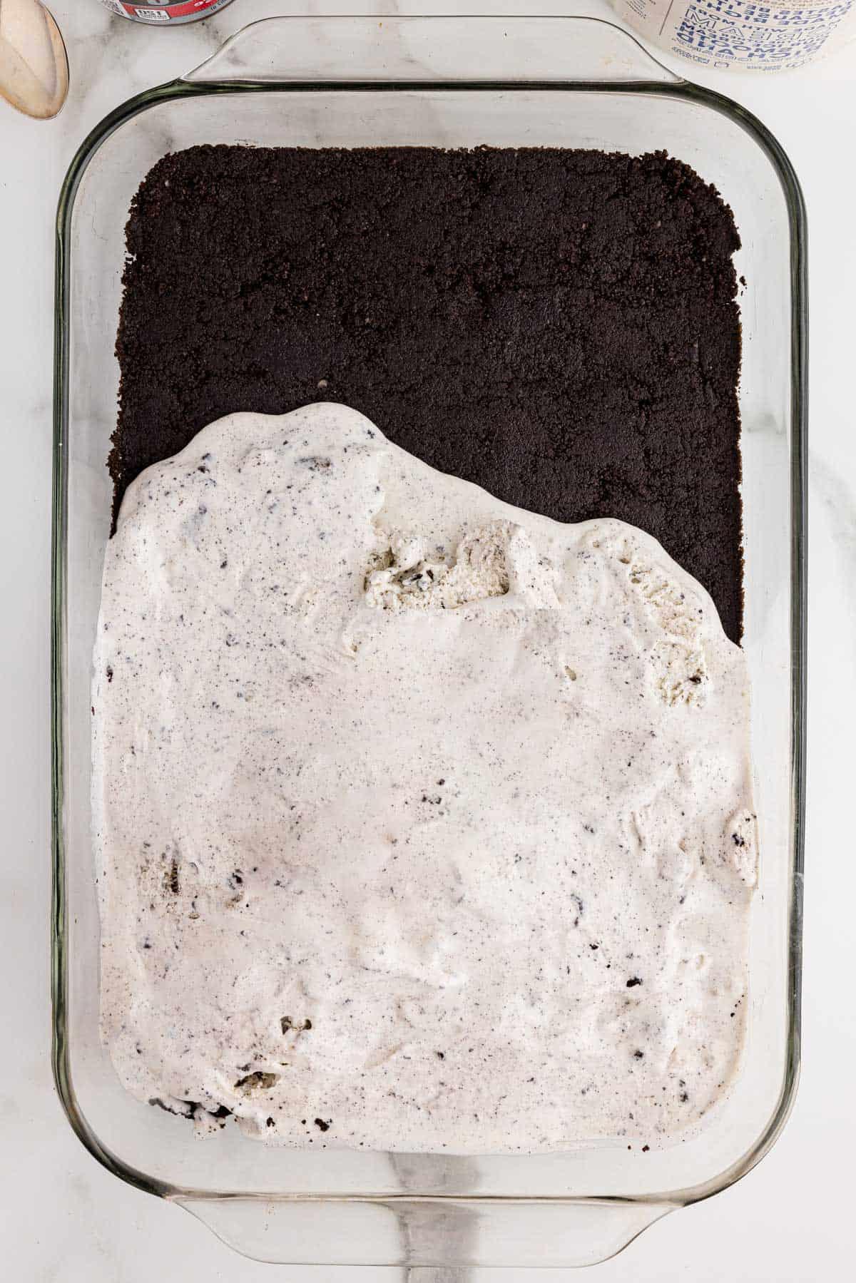 Ricetta Torta Gelato Oreo con 5 Ingredienti 6 Stati di torta gelato Oreo vengono aggiunti a una pirofila con la crosta di Oreo sul fondo e il gelato ai biscotti e panna semi-spalmato sopra