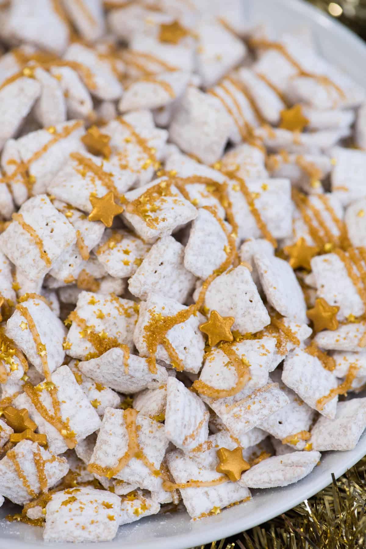 **Dolcetti Croccanti al Cioccolato Bianco di Capodanno** 6 new year’s eve white chocolate puppy chow with gold sprinkles and gold stars inside a white bowl