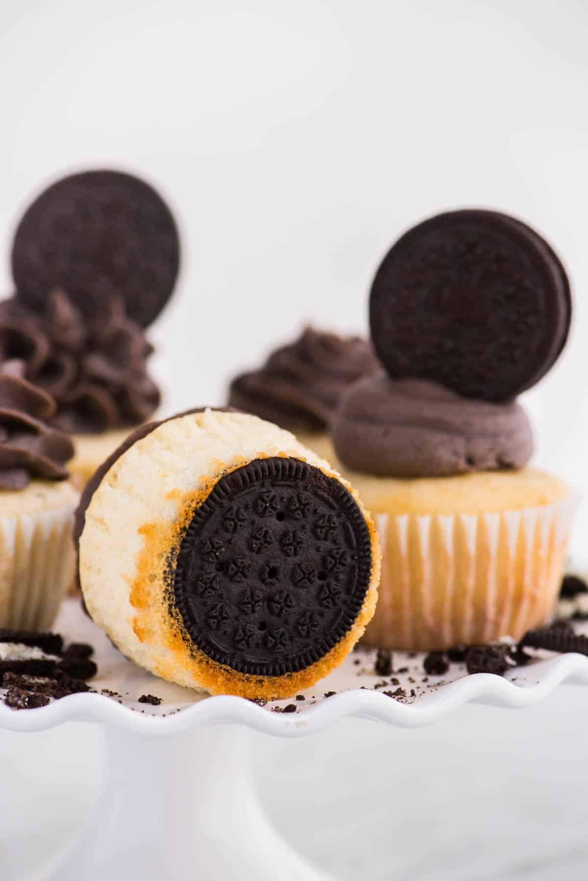 Cupcakes alla vaniglia con fondo Oreo su alzata bianca su sfondo bianco