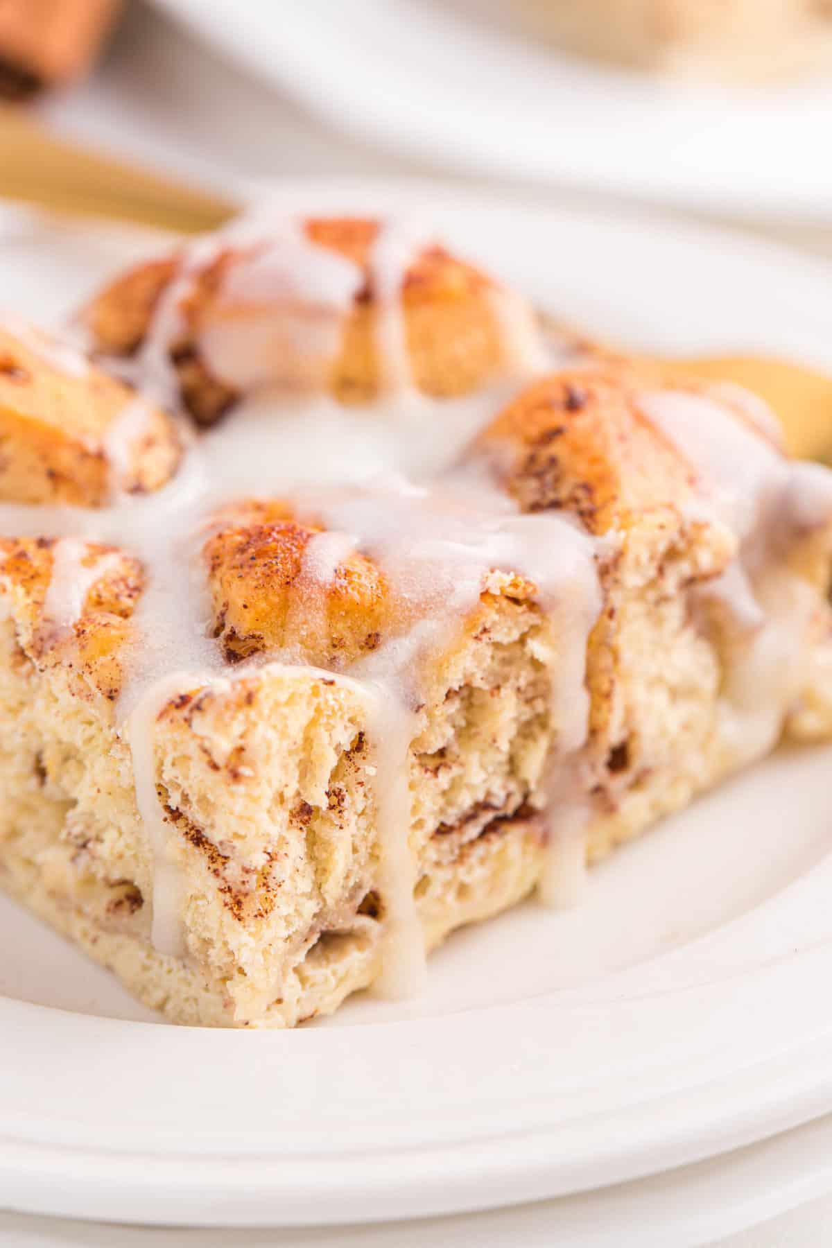 slice of cinnamon roll casserole with icing on white plate