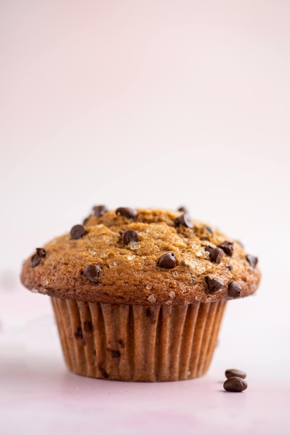 Muffin al Cappuccino e Gocce 7 un muffin al cappuccino con gocce di cioccolato su una superficie bianca e rosa chiaro