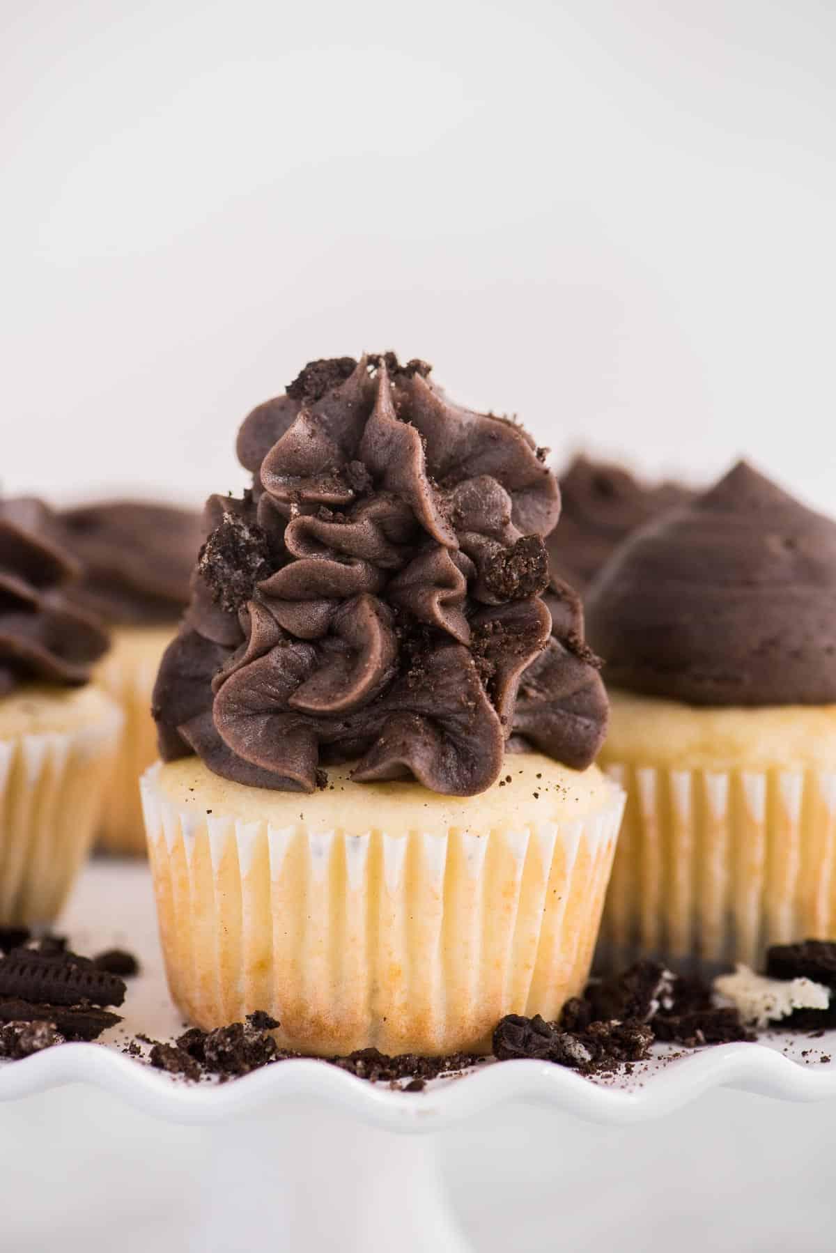 Cupcakes alla vaniglia con fondo Oreo su alzata bianca su sfondo bianco