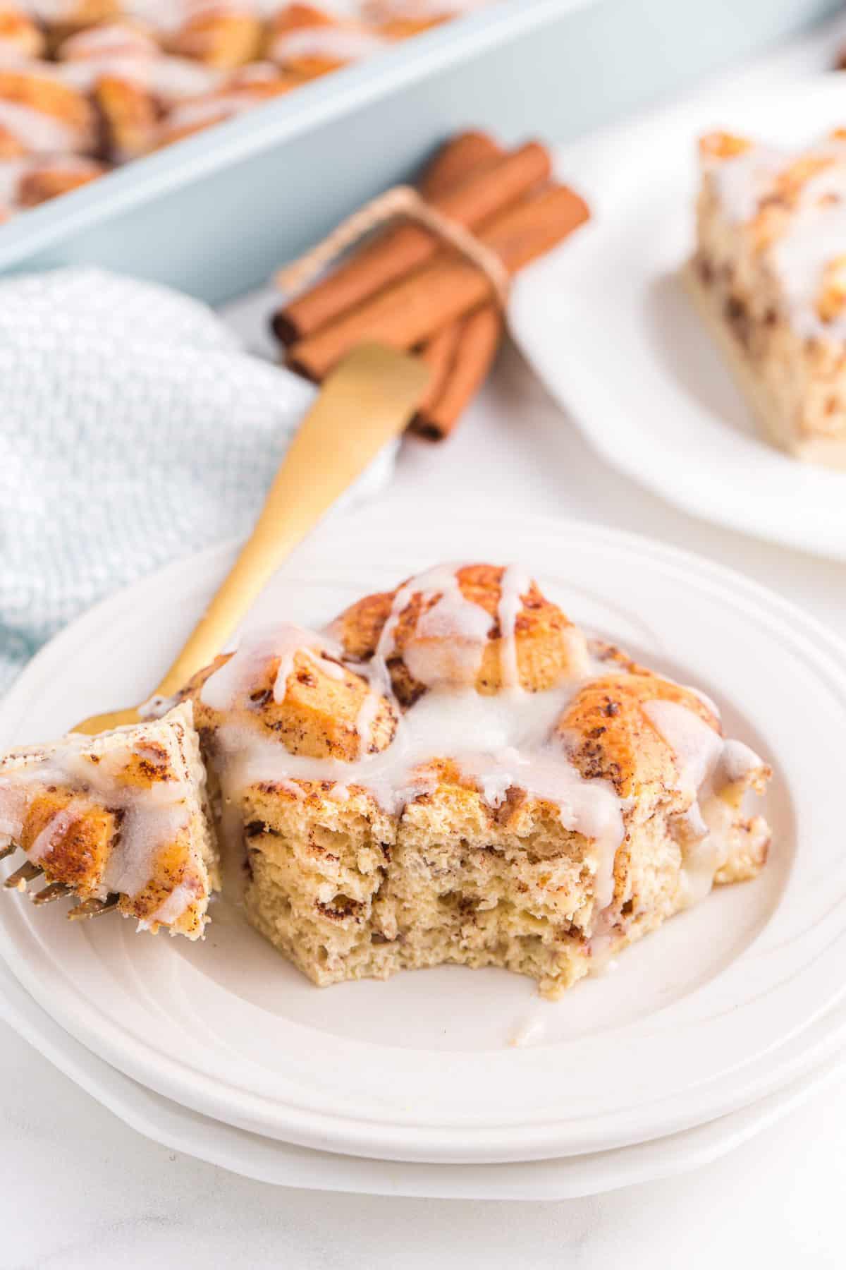 slice of cinnamon roll casserole with icing on white plate