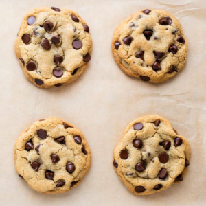 Visuale dall'alto di 4 biscotti con gocce di cioccolato su carta forno