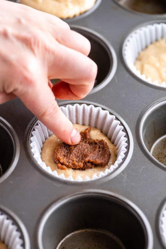 dito che preme la miscela di zucchero e cannella nell'impasto del muffin